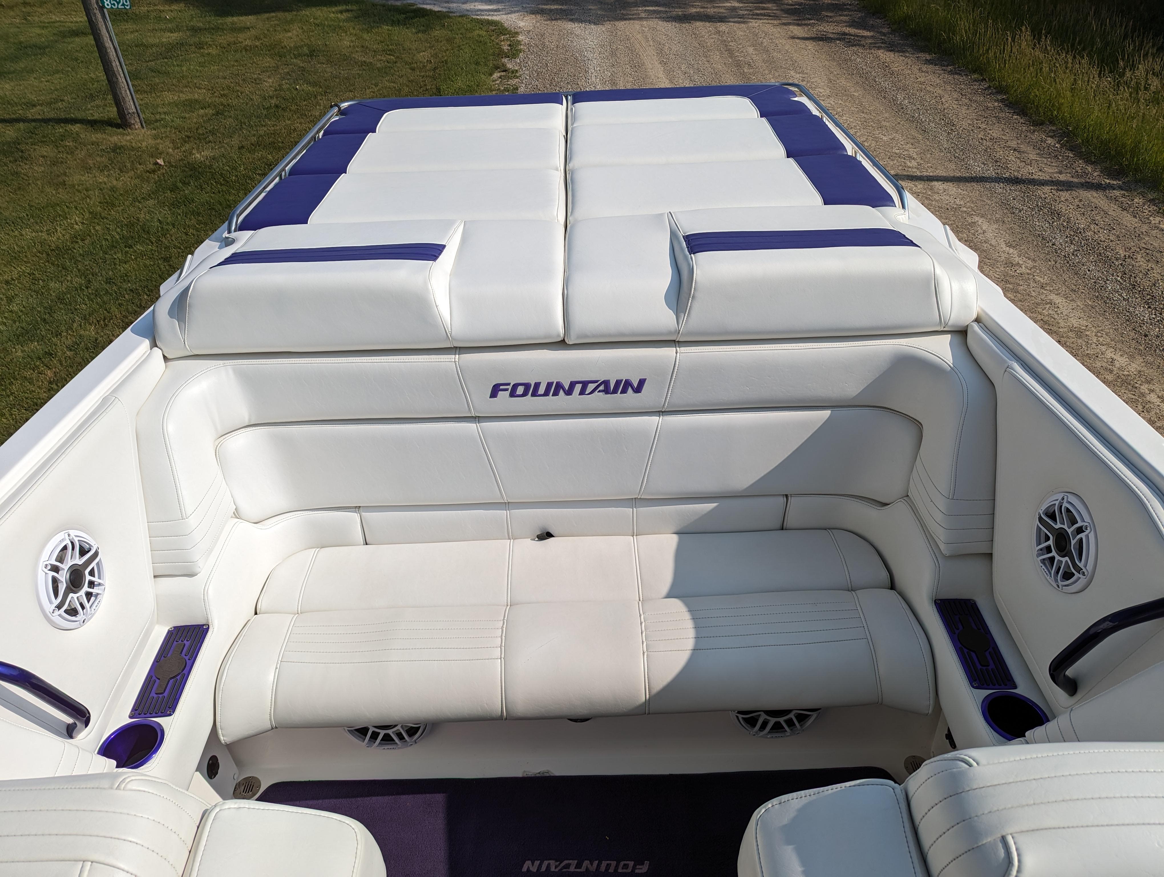 White and purple interior of a 2006 Fountain 42 boat, featuring cushioned seating.
