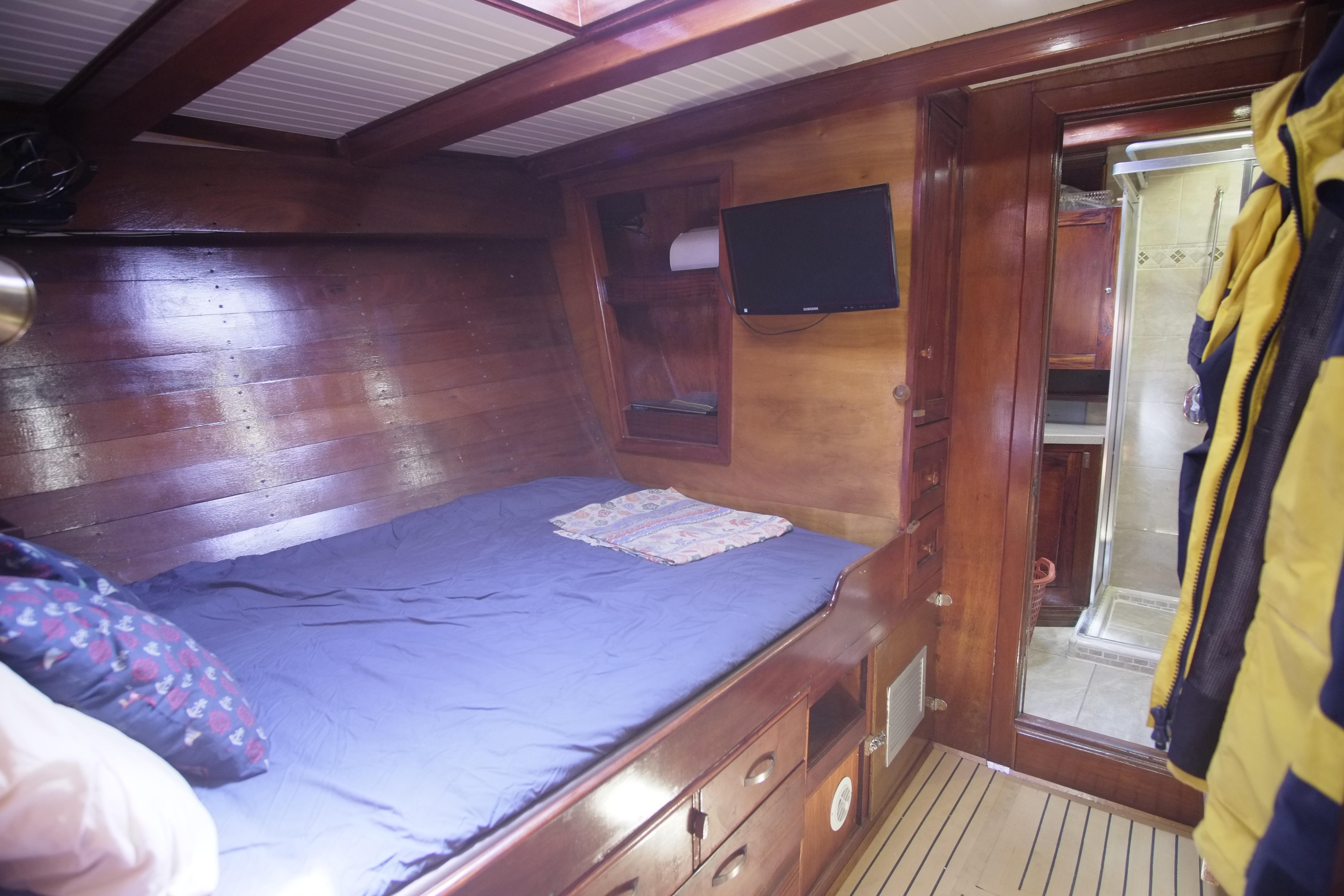 Cozy cabin interior of 2006 Custom Bud Macintosh schooner with wooden finish and bed.