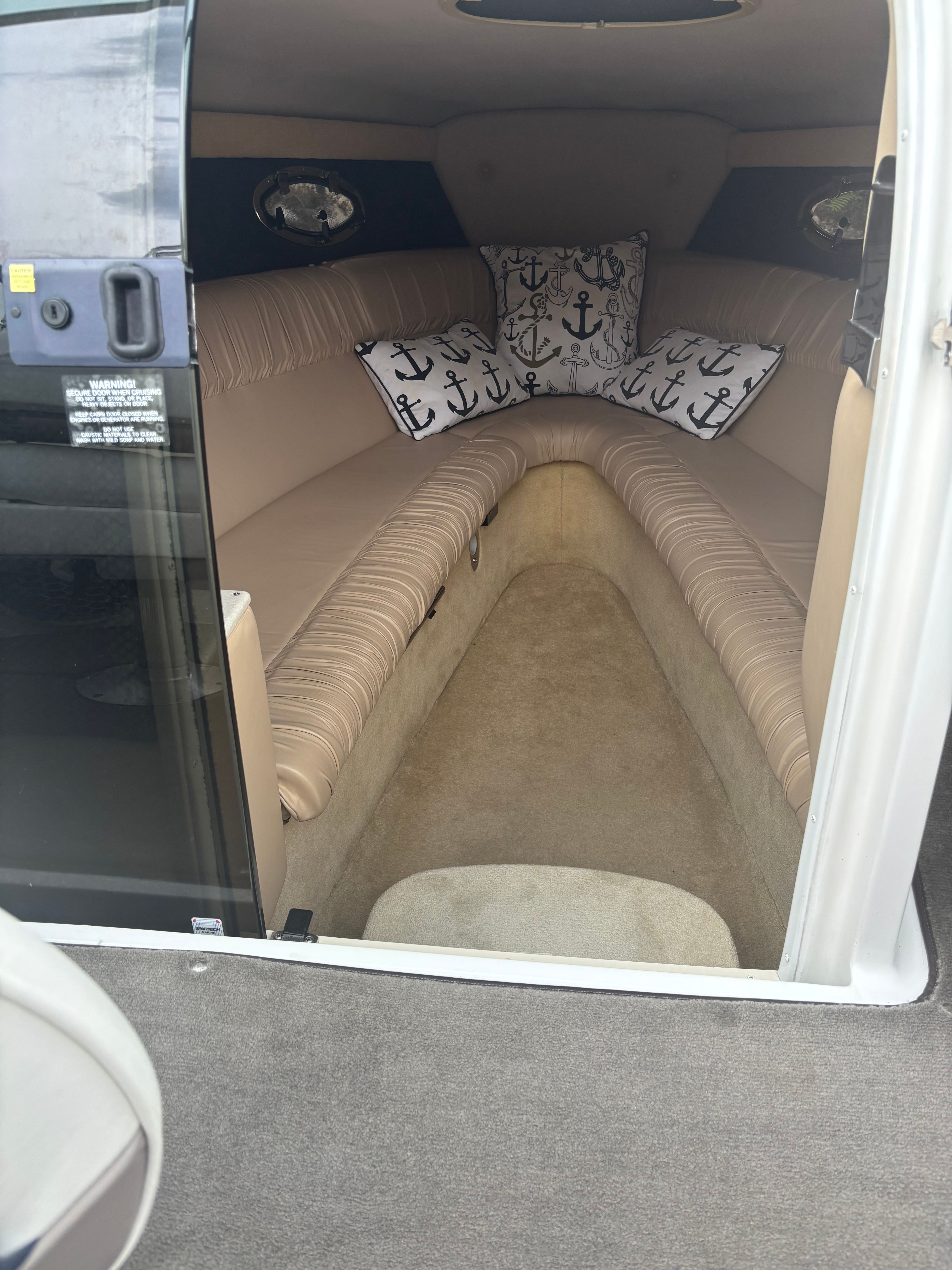 Interior of a 2005 Cobalt 255 with cushioned seating and anchor-themed pillows.