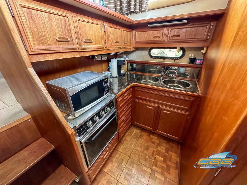 1989 Carver 3807 Aft Cabin kitchen with wood cabinets, microwave, and dual sinks.