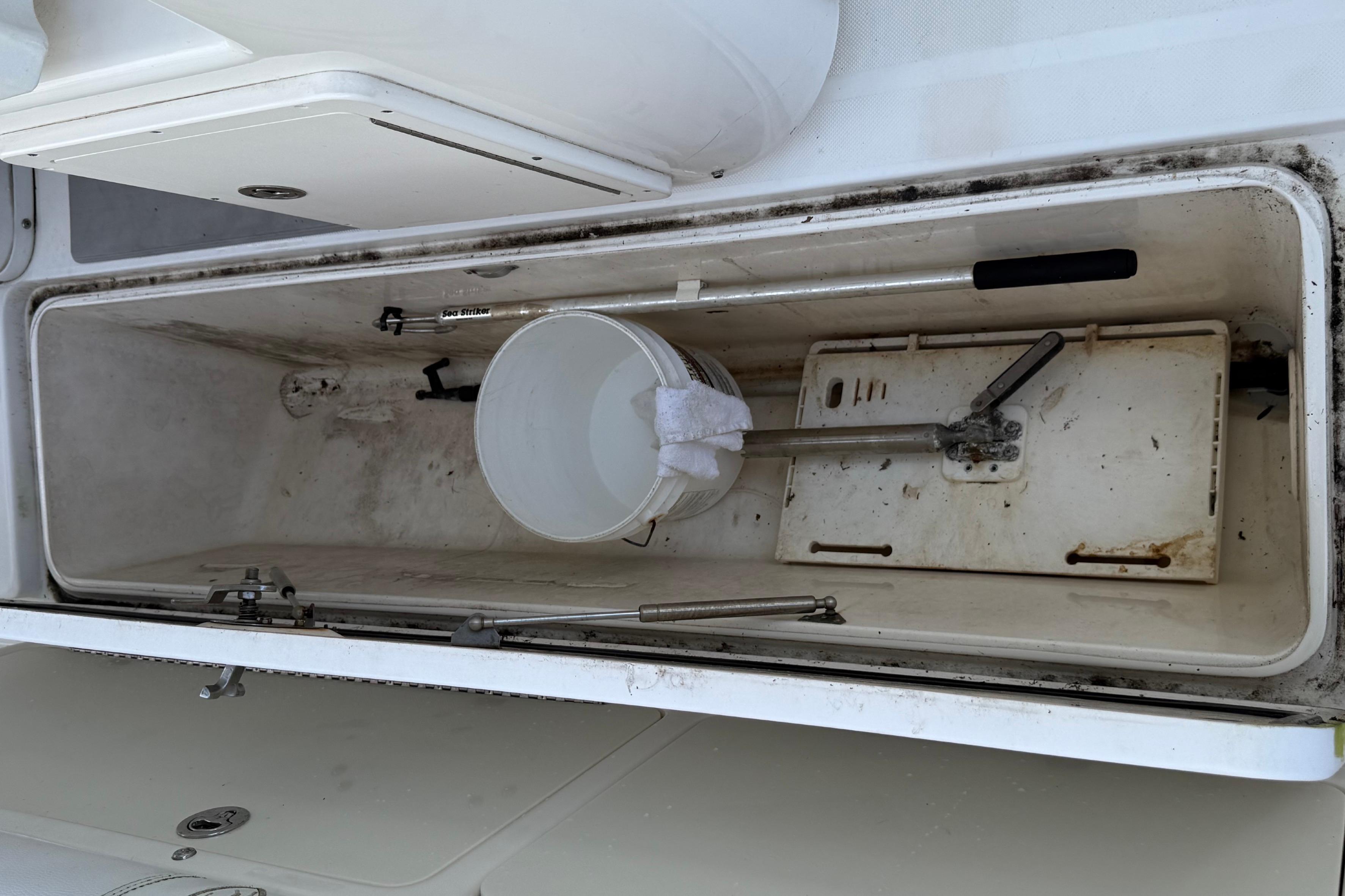 Open storage compartment on 2008 Century 2901 Center Console boat with tools and bucket.