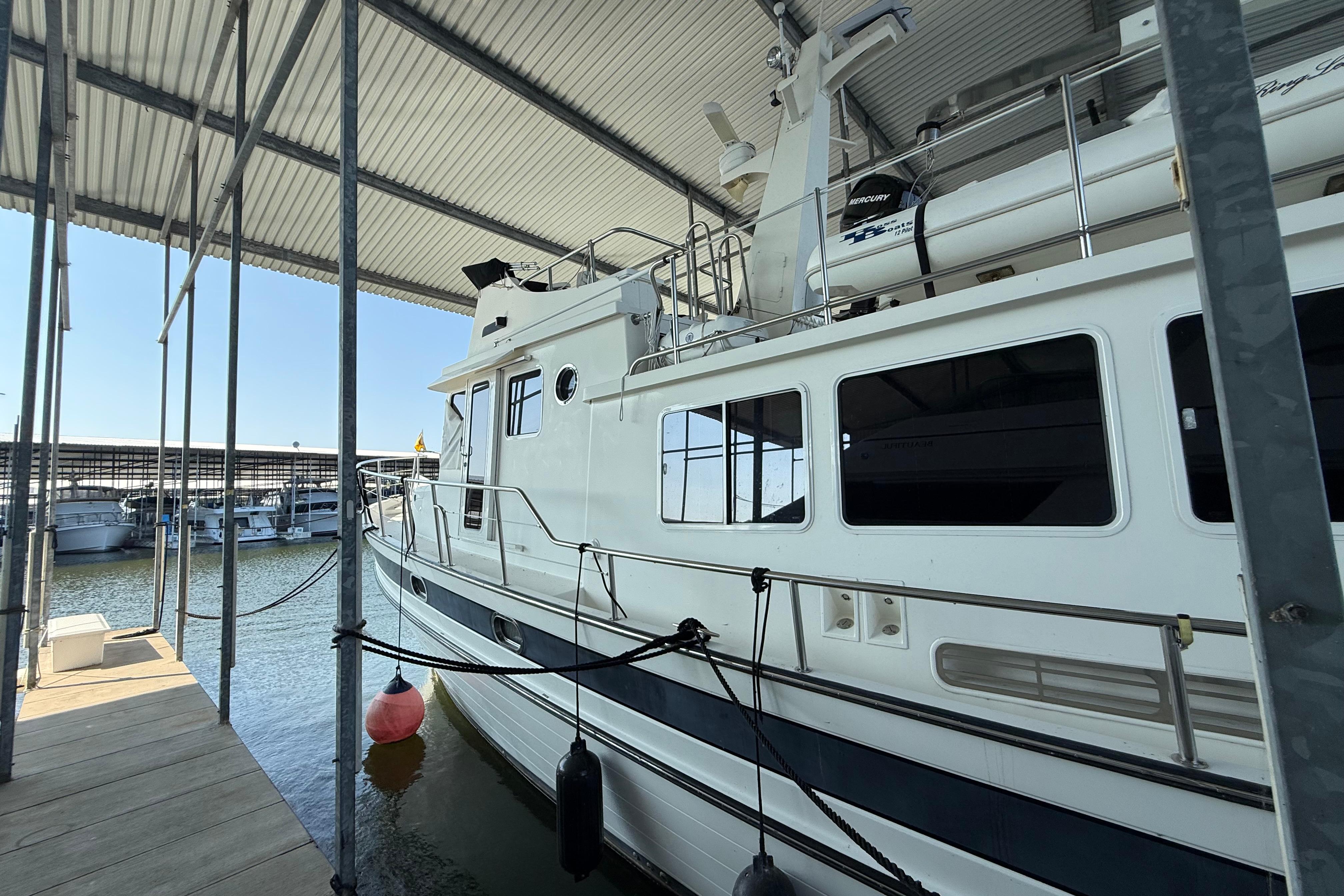 2007 Nordic Tug 54 docked in a covered marina, side view.