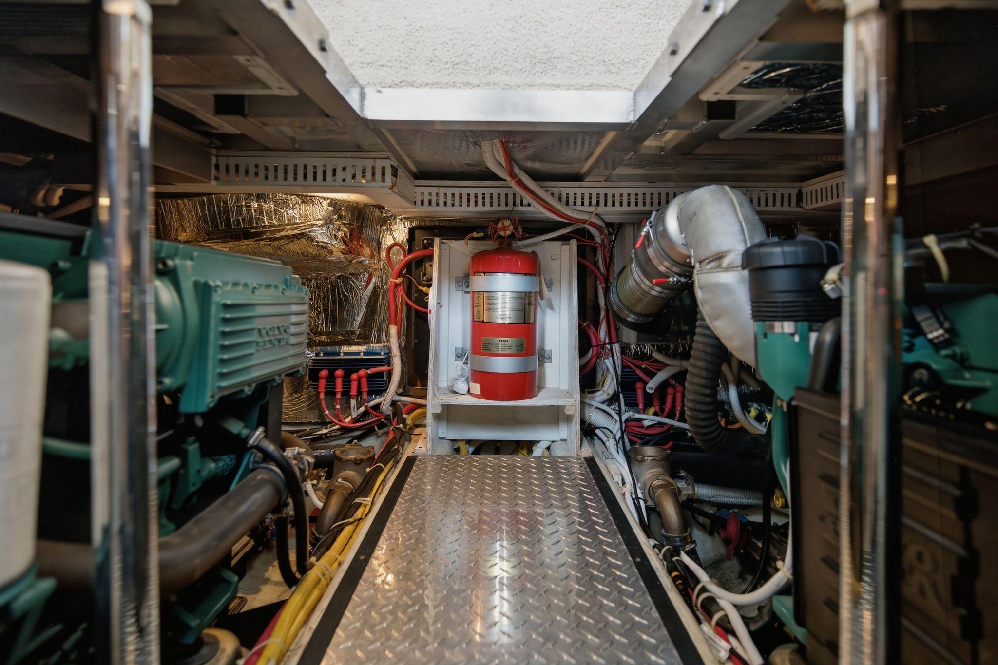 Engine room of 2005 Carver 39 Motor Yacht with visible machinery and fire extinguisher.