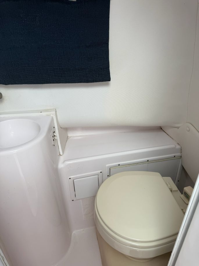 The image shows a boat toilet with a sink and a towel.