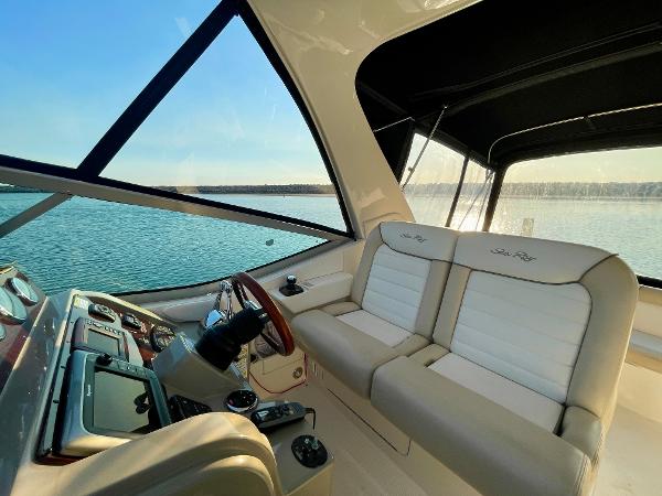 2014 Sea Ray 330 Sundancer interior with beige seating and helm, overlooking serene water.