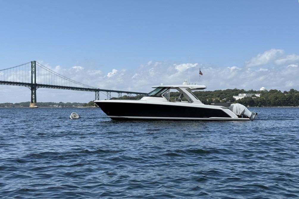 2021 Tiara Sport 38 LS boat on water near bridge, clear sky background.