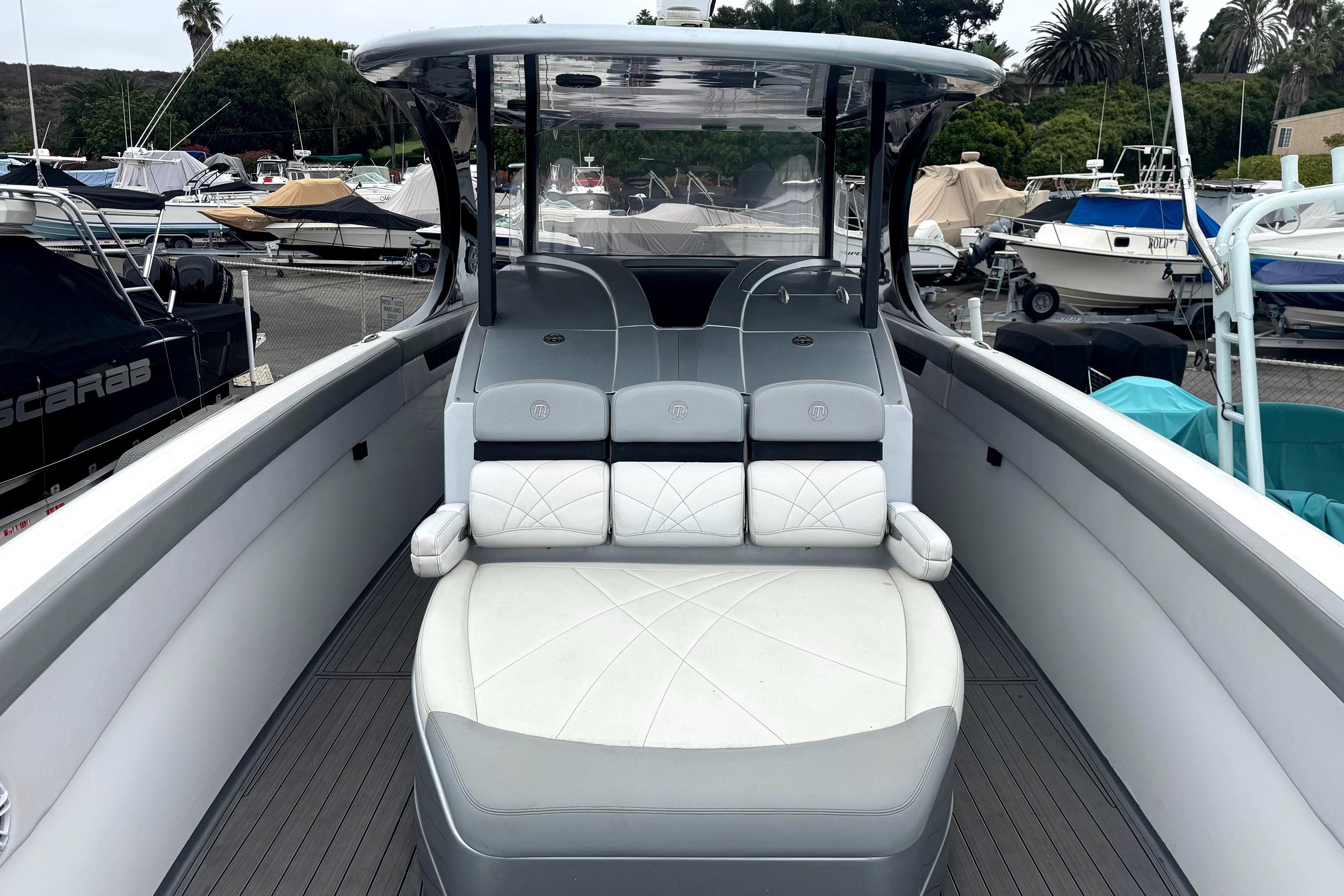 2016 Mystic M4200 boat with sleek seating, docked among other vessels.