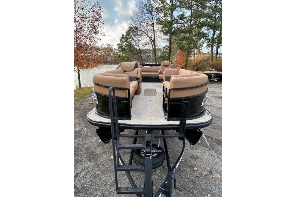 2025 Regency 230 LE3 Sport pontoon boat with tan seating, parked near a lake.