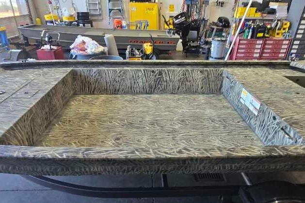 2026 Tracker Grizzly 1648 Utility boat with camouflage interior in a workshop setting.