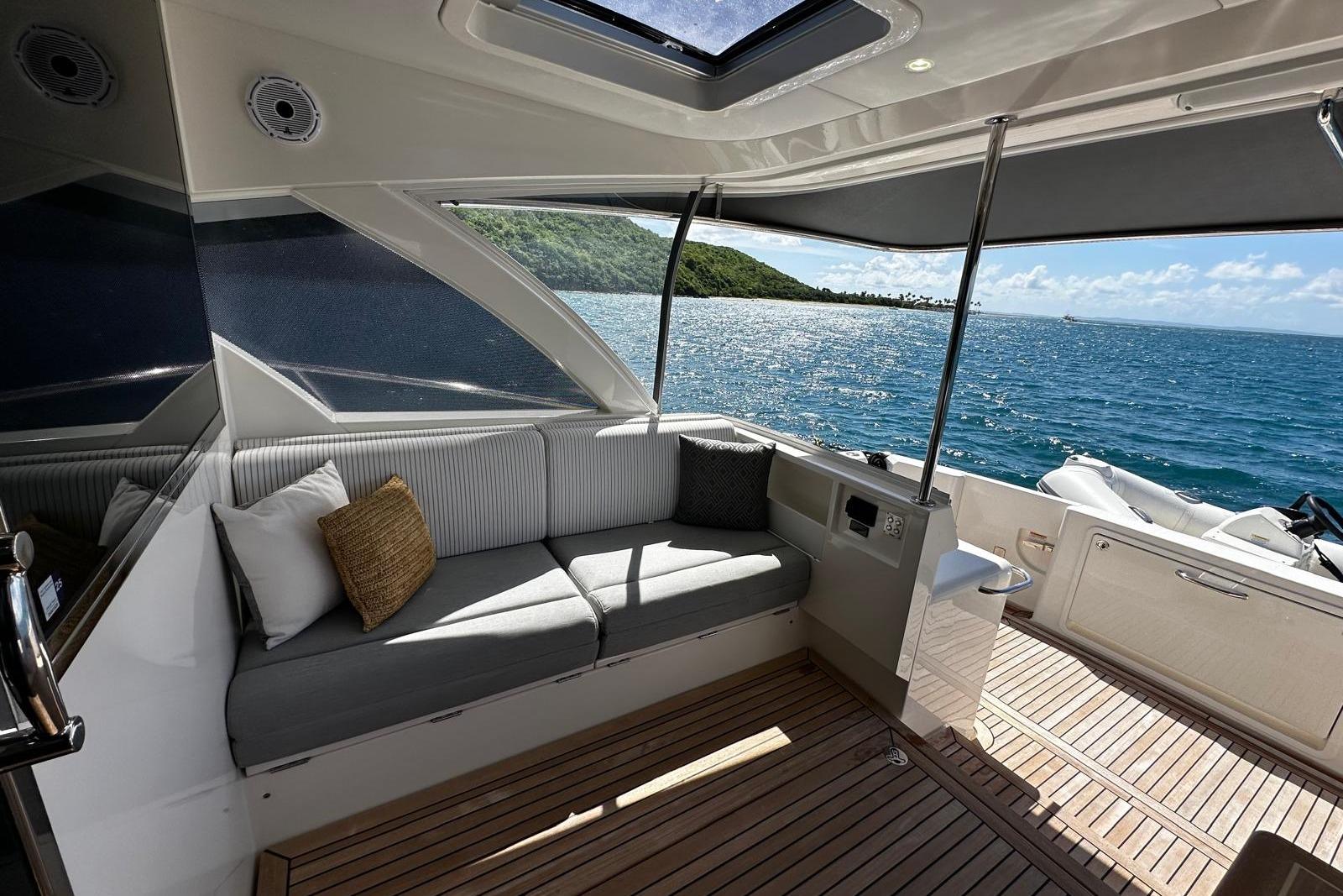 Luxurious 2023 Riviera 465 SUV yacht interior with ocean view and comfortable seating.