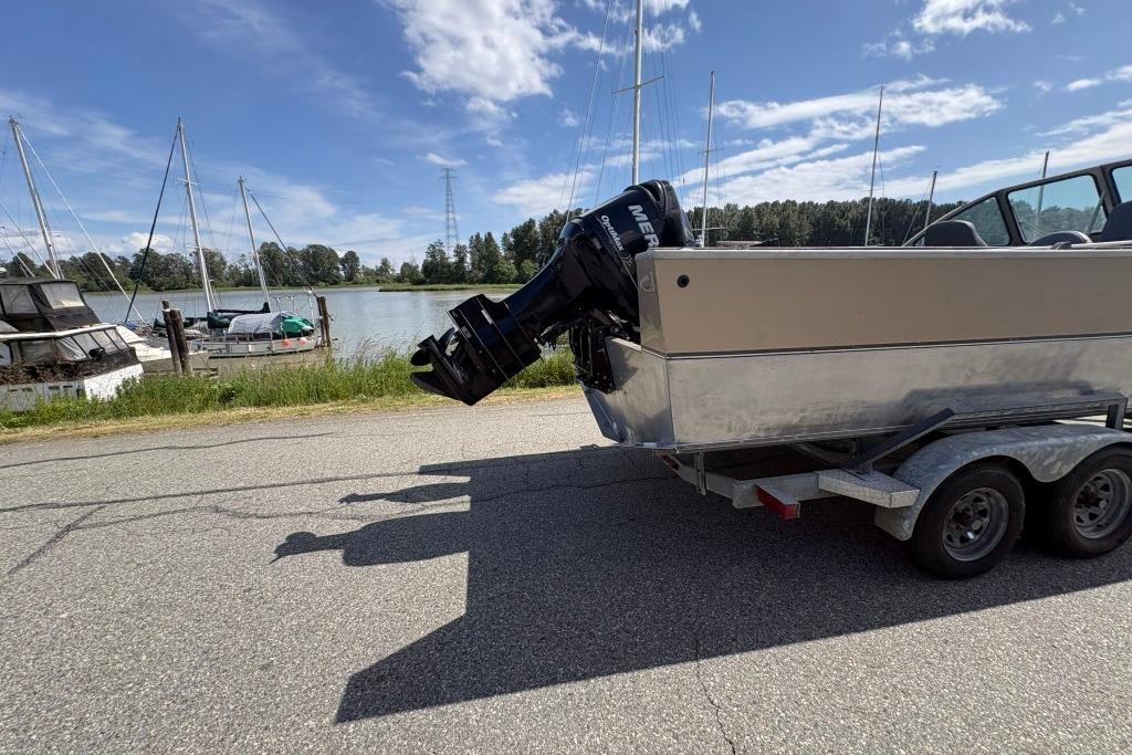 2009 Alumaweld Intruder Outboard 22 on trailer by riverside, under clear blue sky.
