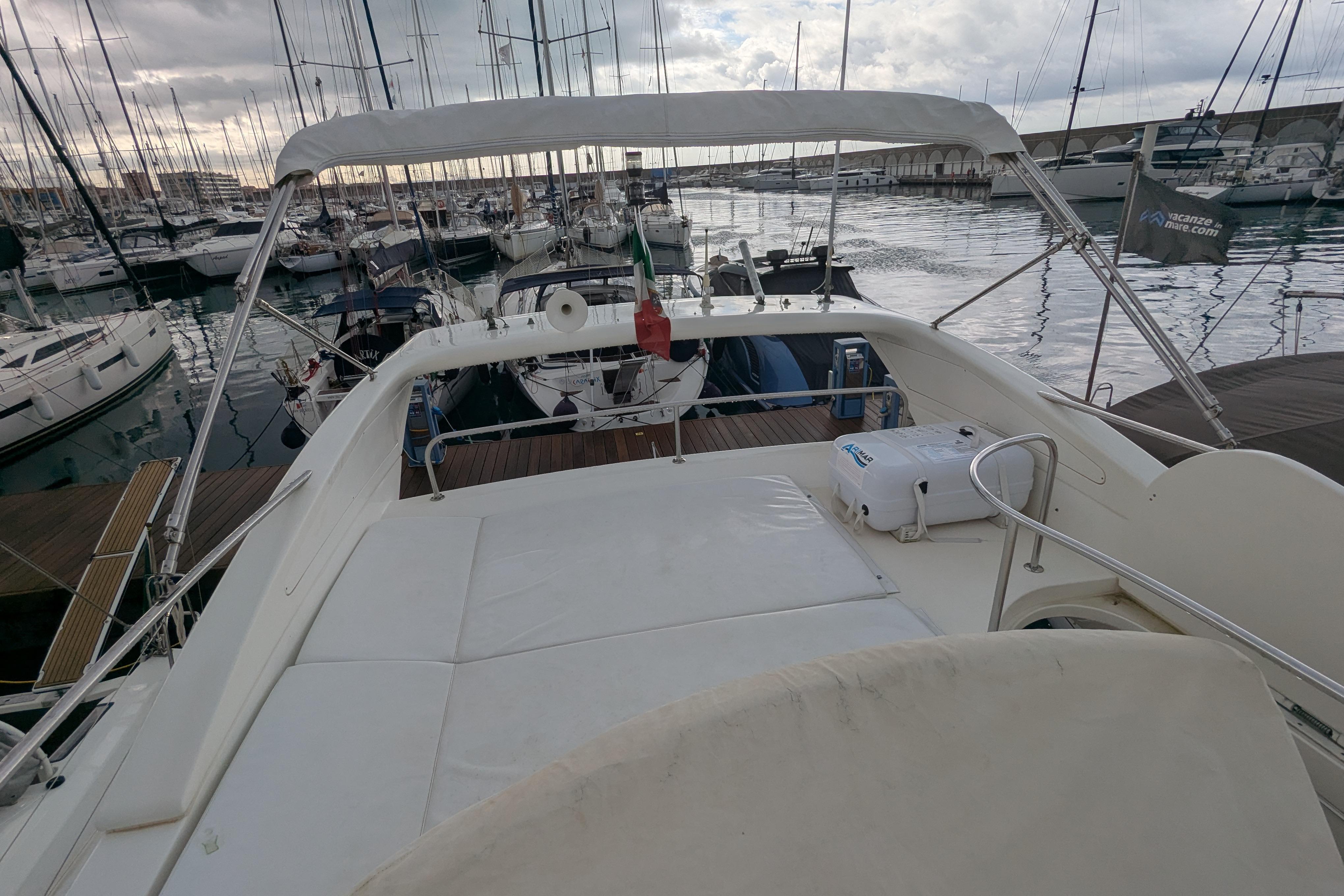 Azimut 46 yacht from 2000 docked in a marina, surrounded by sailboats.