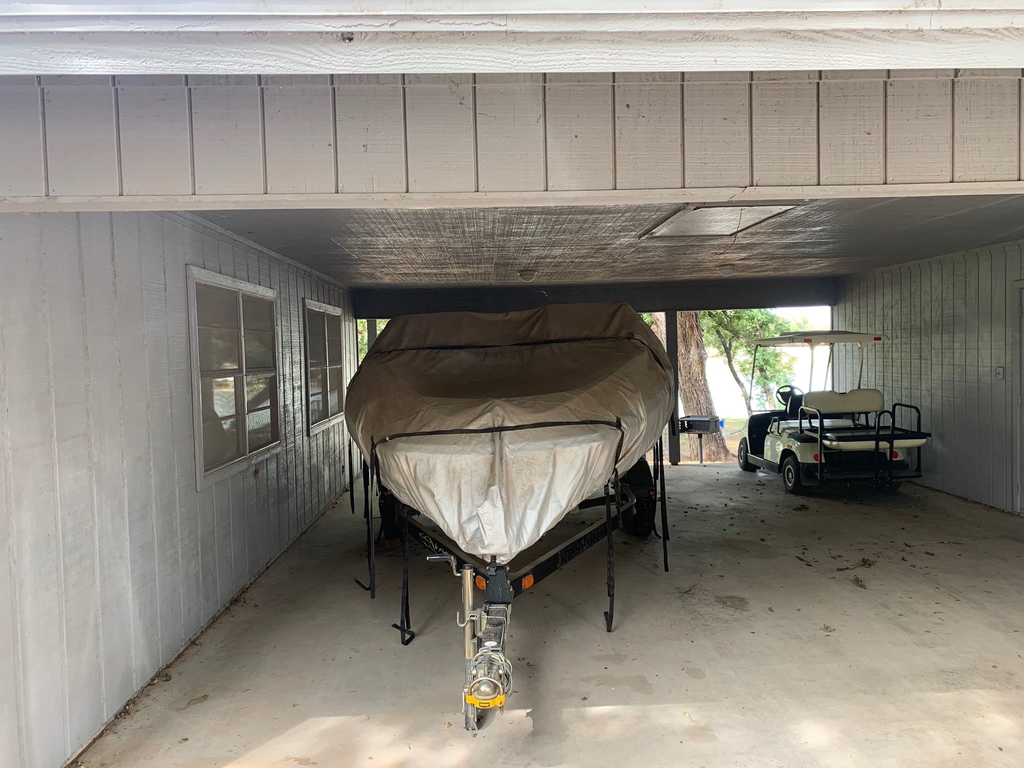 2008 Bombardier 180 Challenger boat under carport with golf cart.