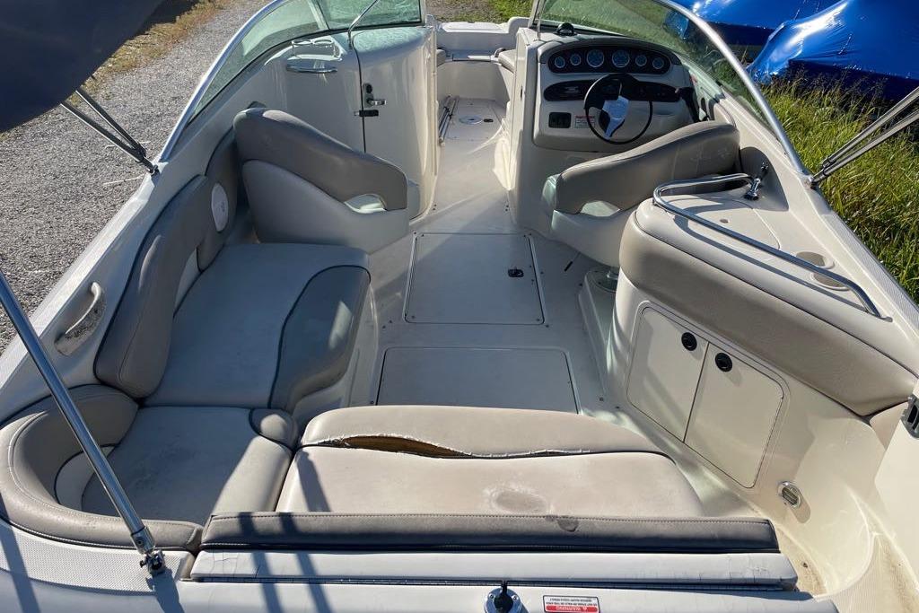 2004 Sea Ray 240 Sundeck interior with seating and steering wheel, showing wear.
