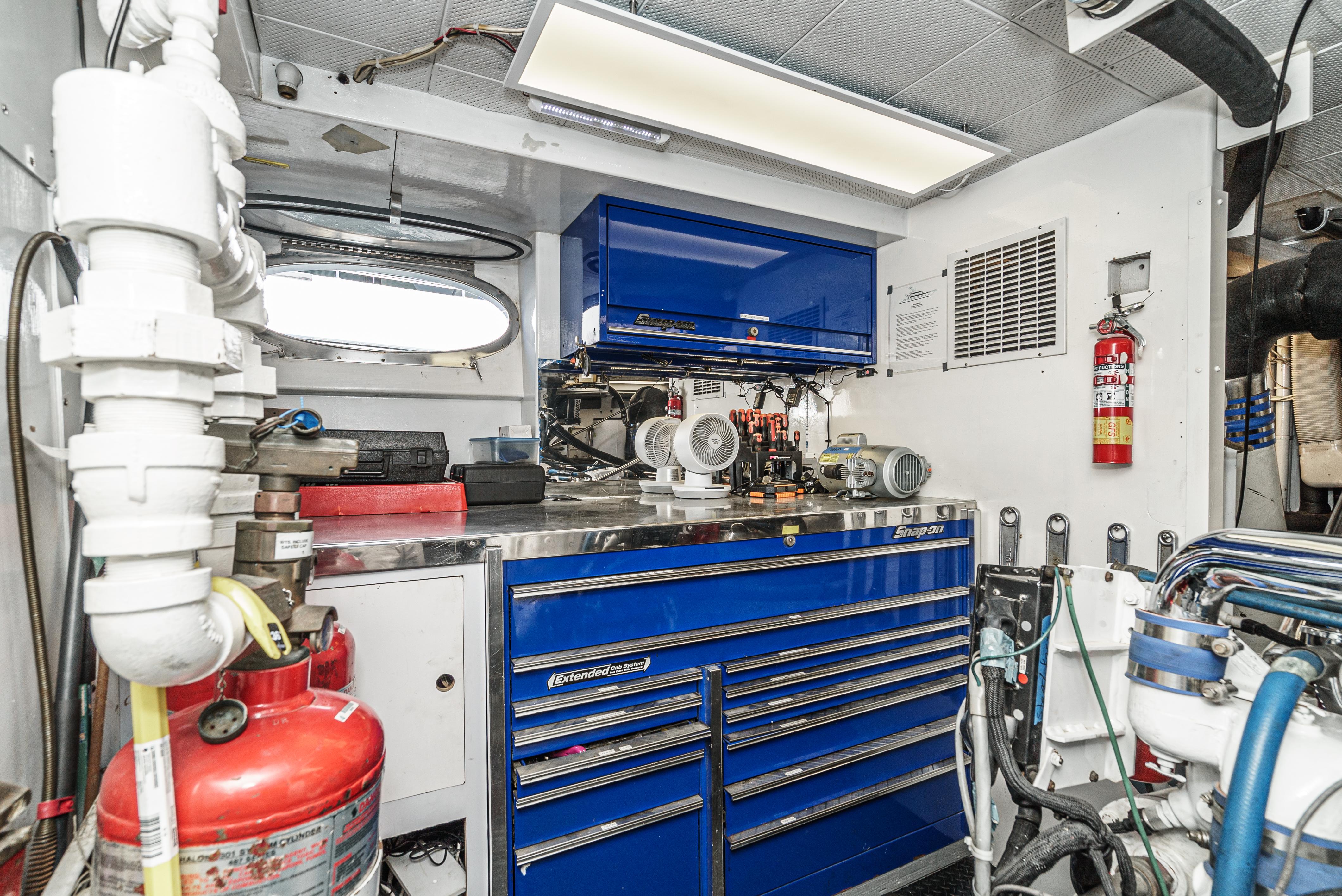 Engine room of 1992 Barattucci Yacht Fisher with blue tool cabinets and safety equipment.