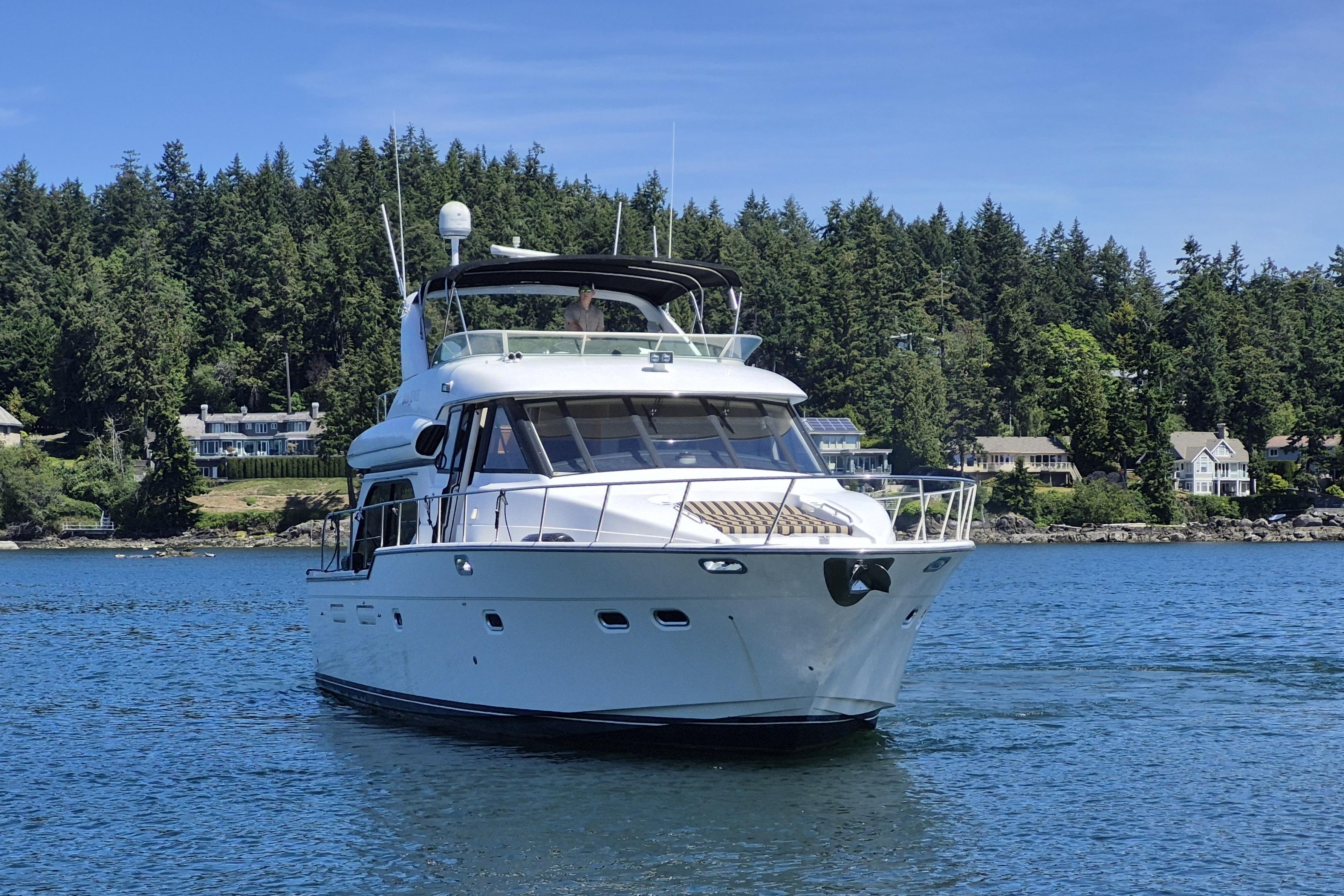 1998 Bayliner 5788 Pilot House Motoryacht on scenic water with forested shoreline.