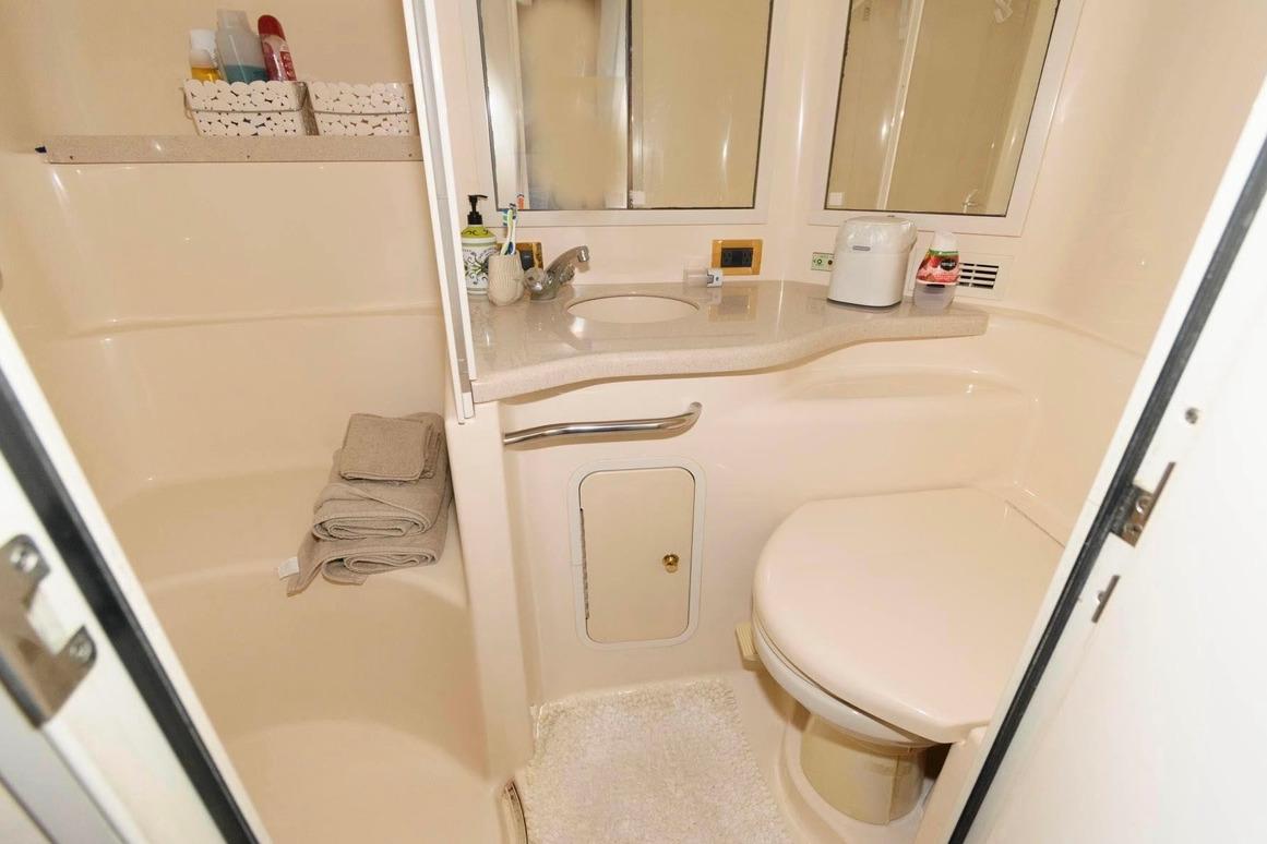 Bathroom interior of 1999 Sea Ray Sundancer 400 yacht, featuring sink, toilet, and storage.