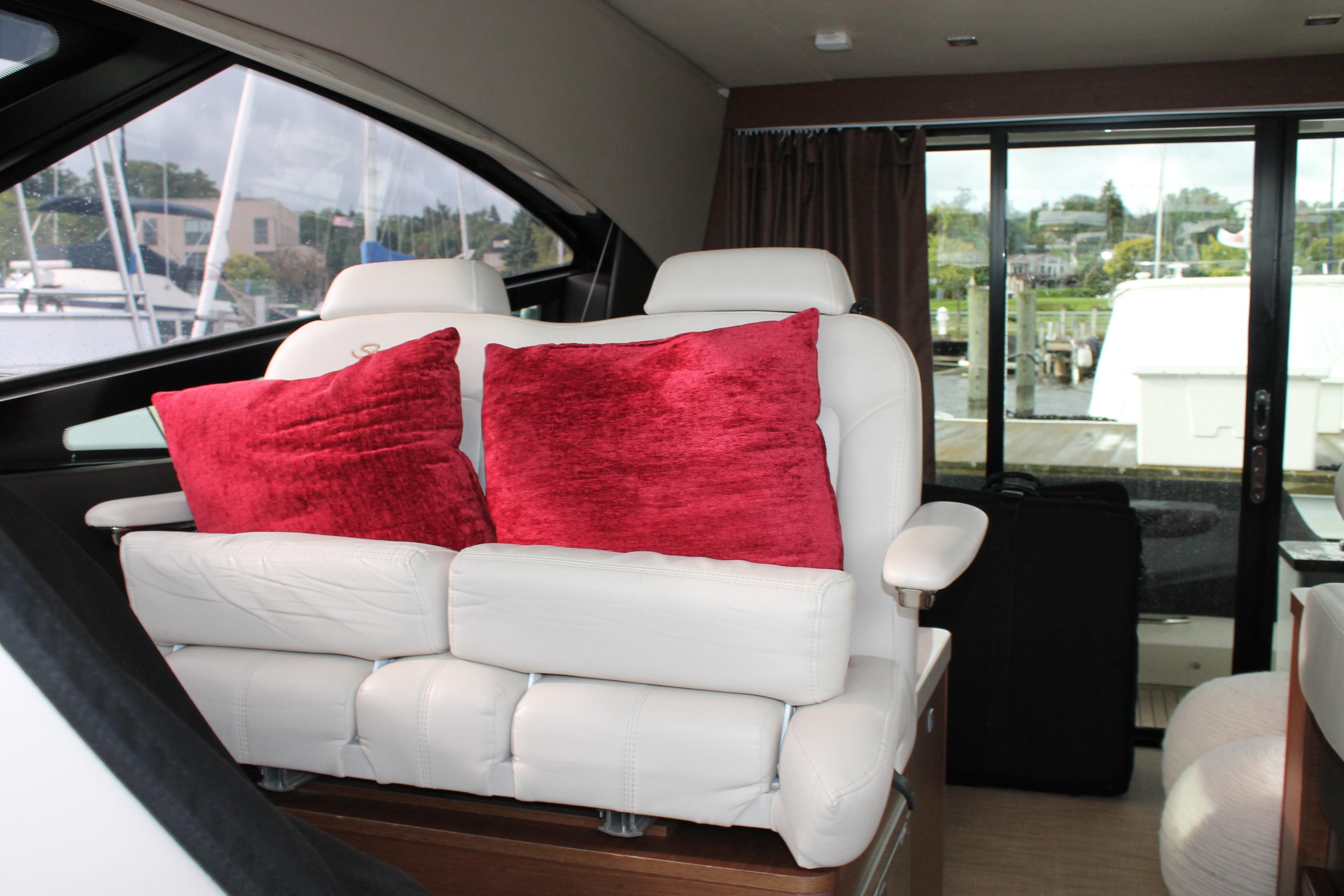 Interior of 2015 Sea Ray 470 Sundancer with white seating and red cushions.