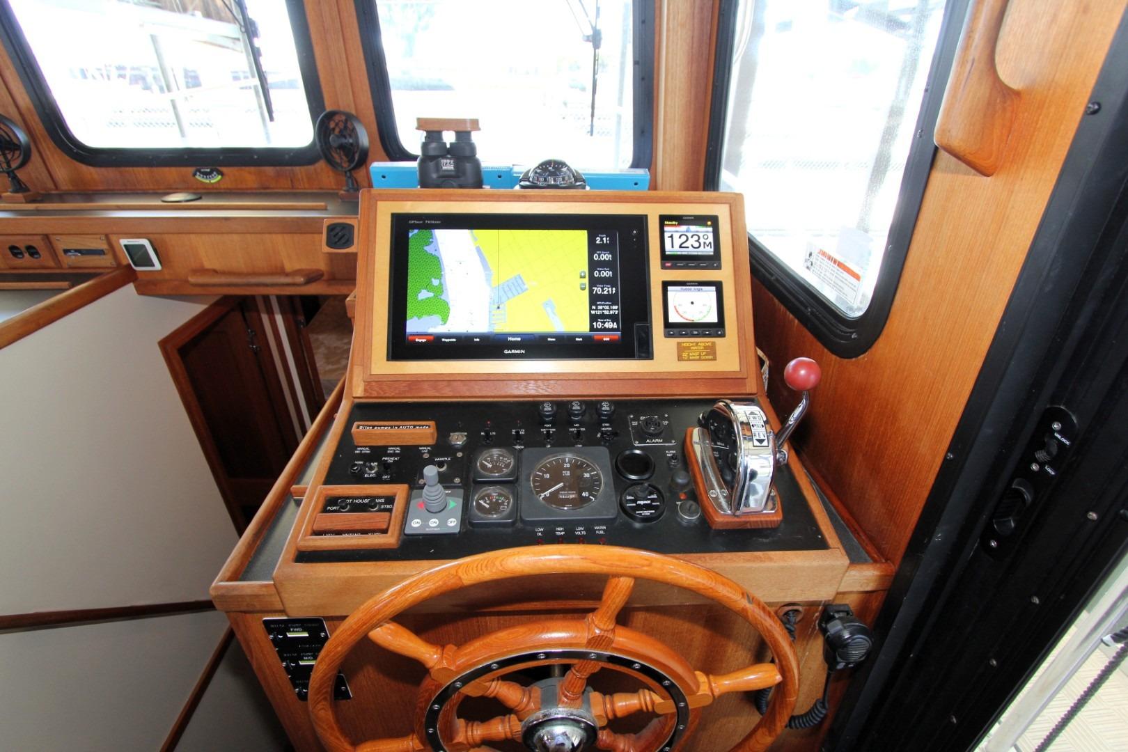 Helm station of 2002 Nordic Tug 37 with navigation equipment and wooden steering wheel.