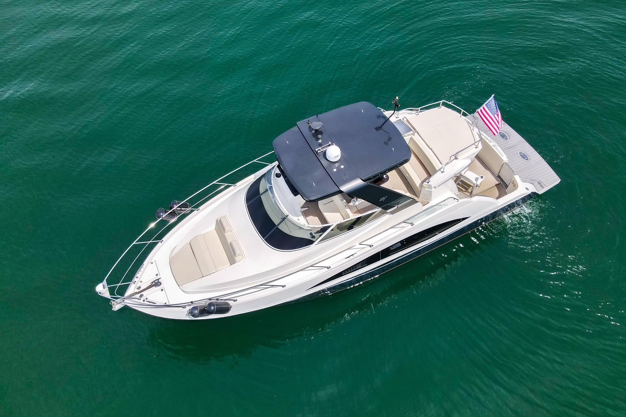2011 Carver 44 Sojourn yacht cruising on clear blue water, aerial view.