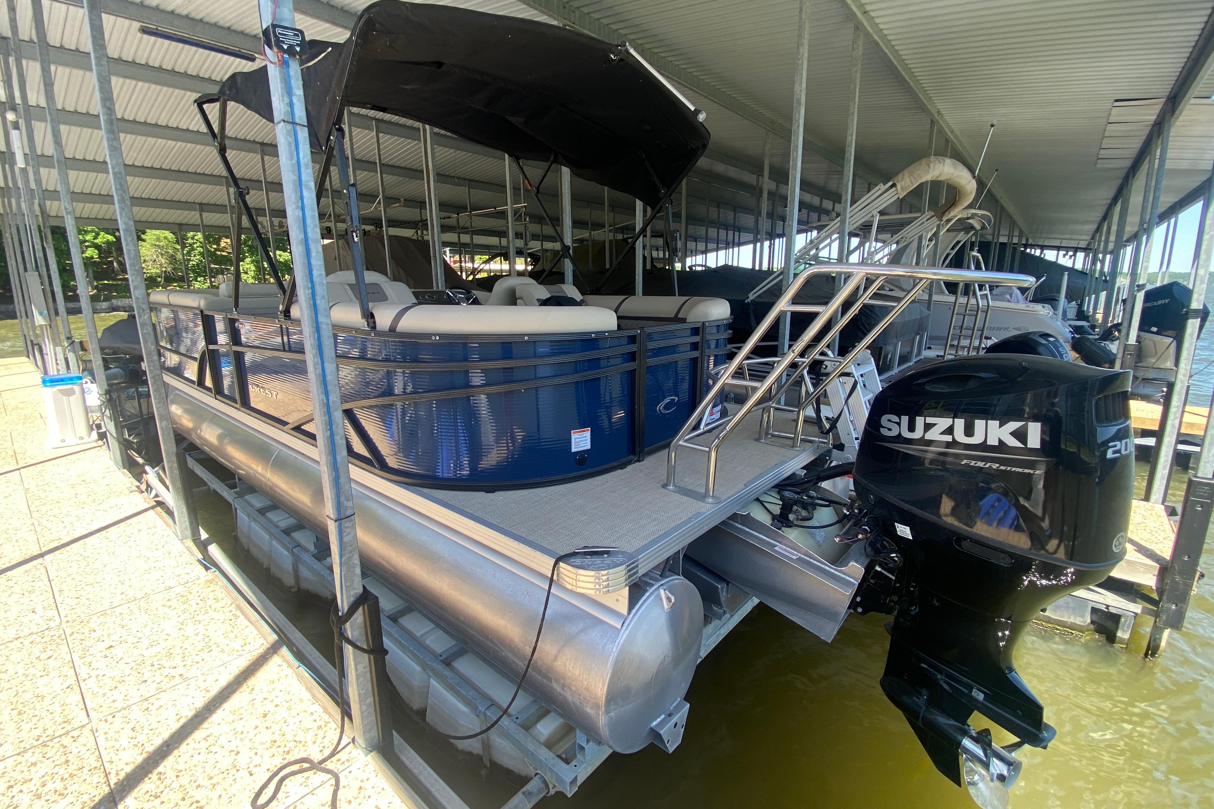 2023 Crest Classic DLX 240 SLC pontoon boat with Suzuki outboard motor docked.