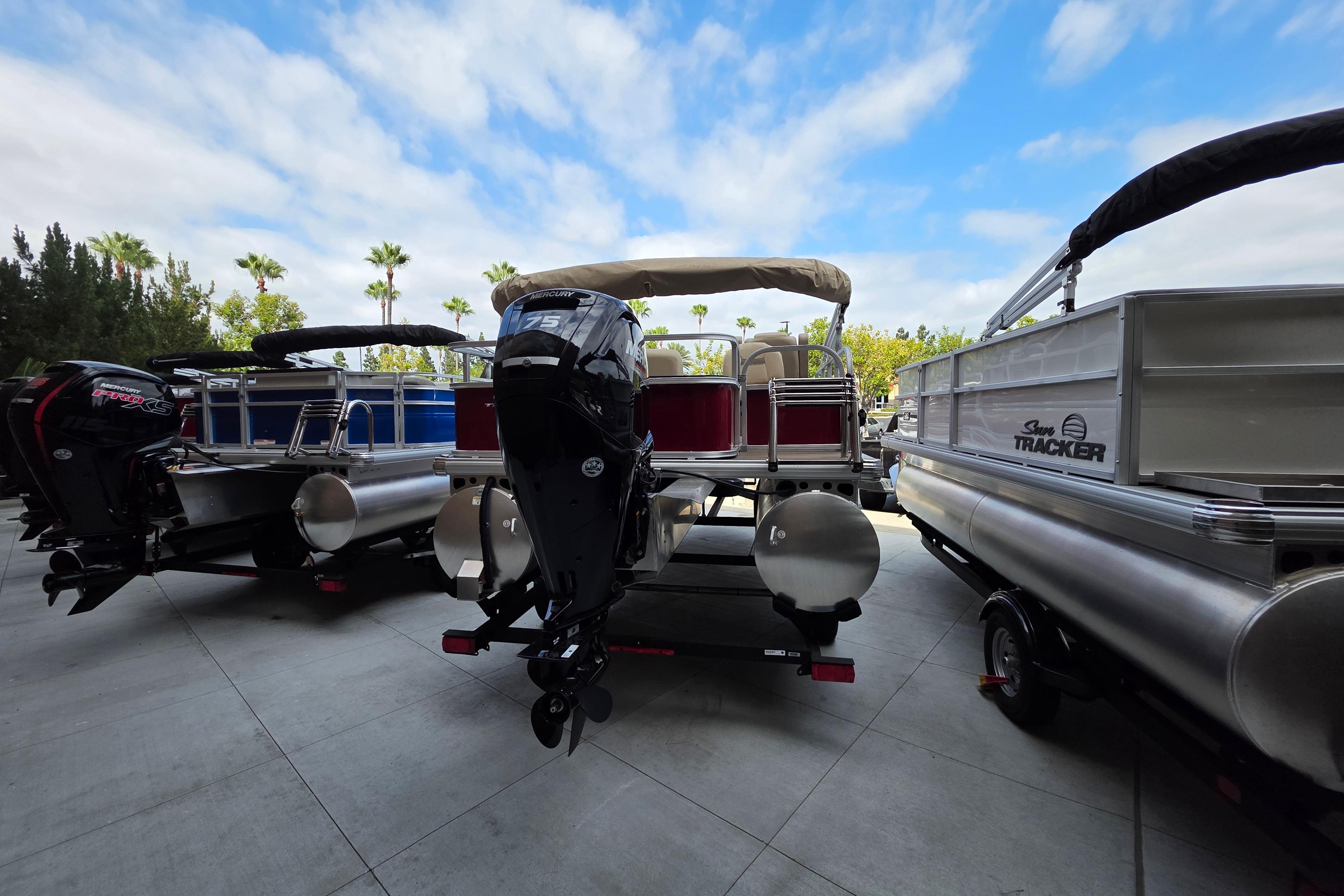 2025 Sun Tracker Bass Buggy 18 DLX pontoon boat with Mercury outboard motor, parked outdoors.