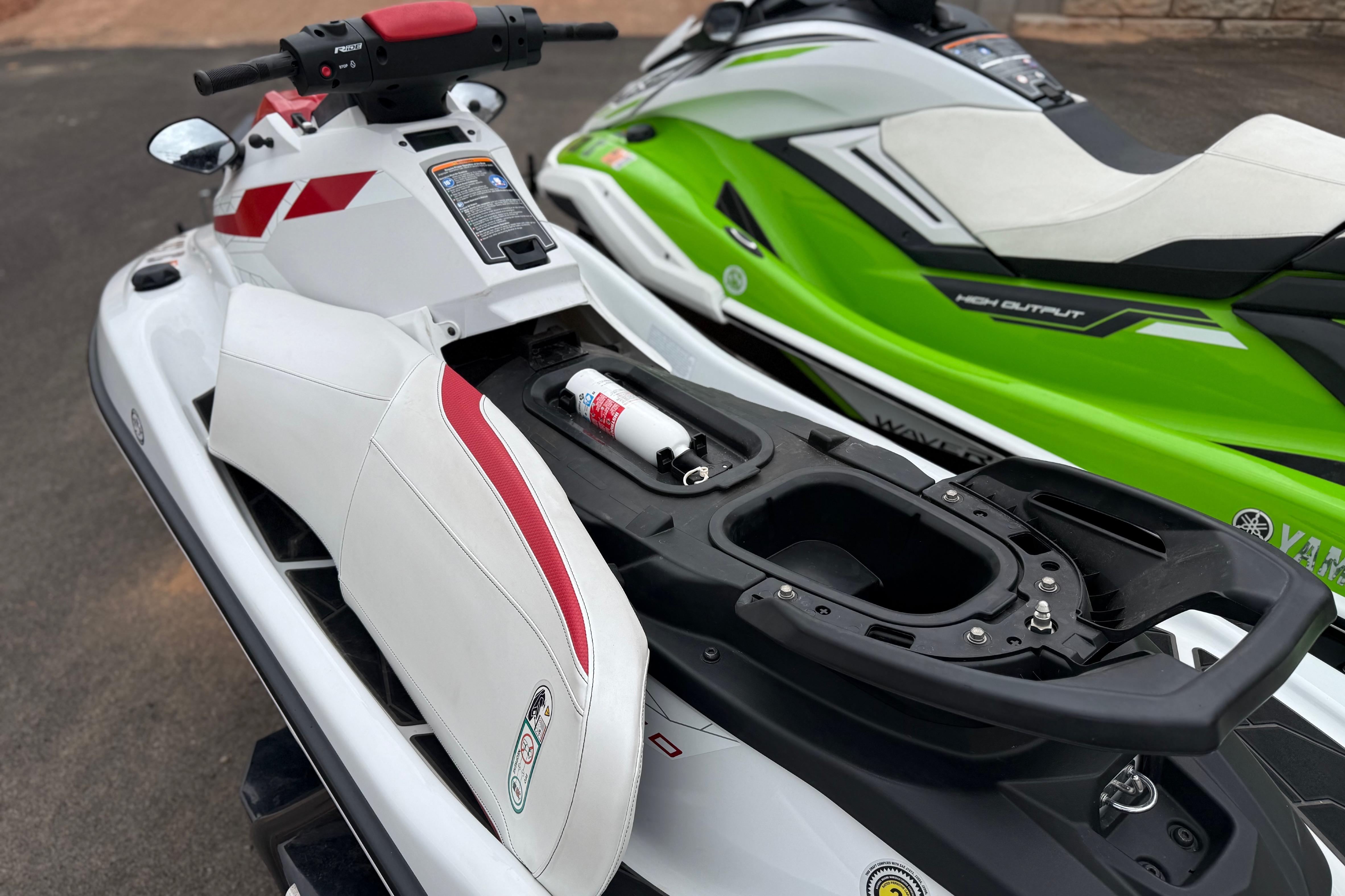 2021 Yamaha WaveRunner EX Limited jet ski with red accents, parked beside a green model.