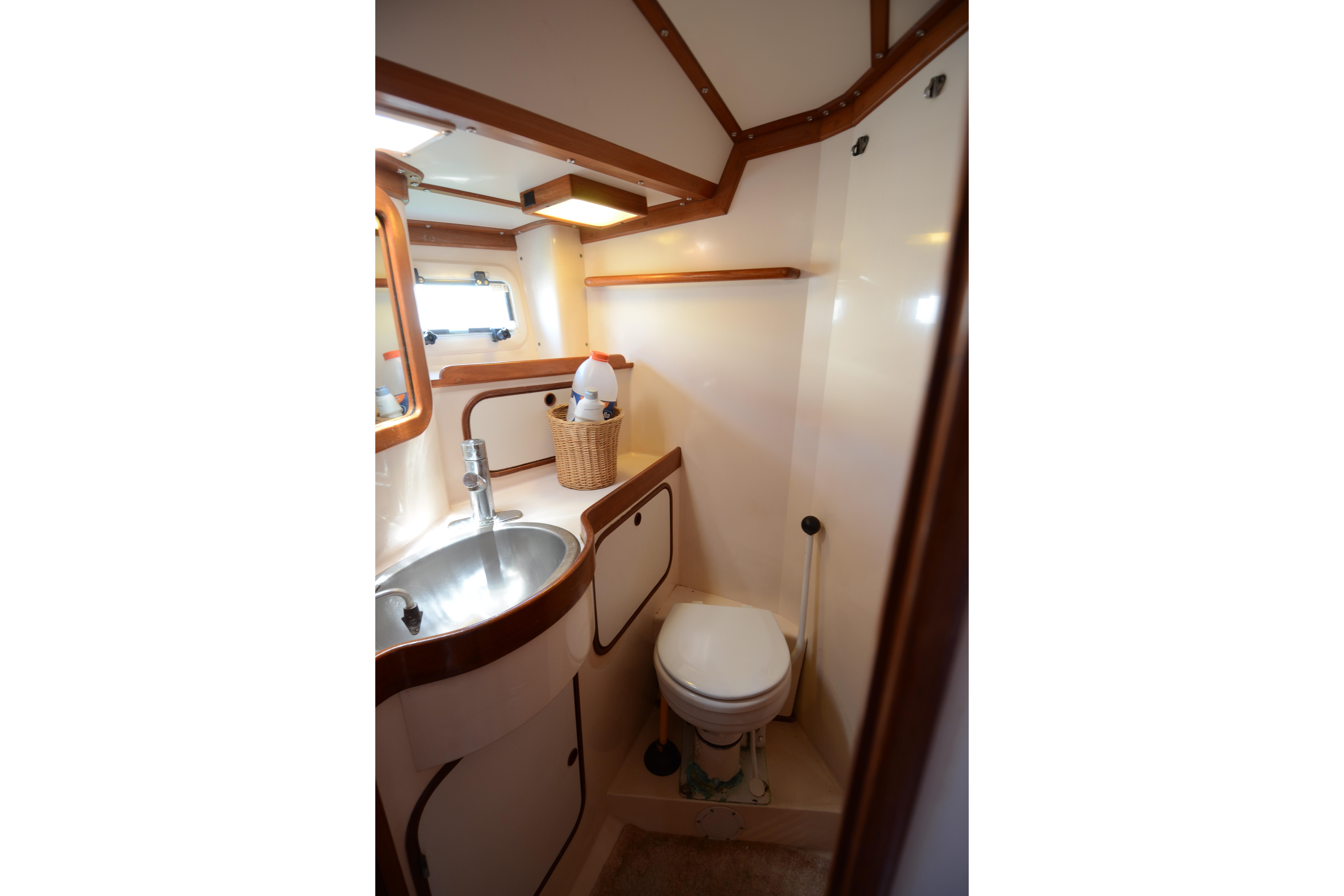 Compact bathroom in 1987 Norseman 400 yacht, featuring sink, toilet, and wooden accents.