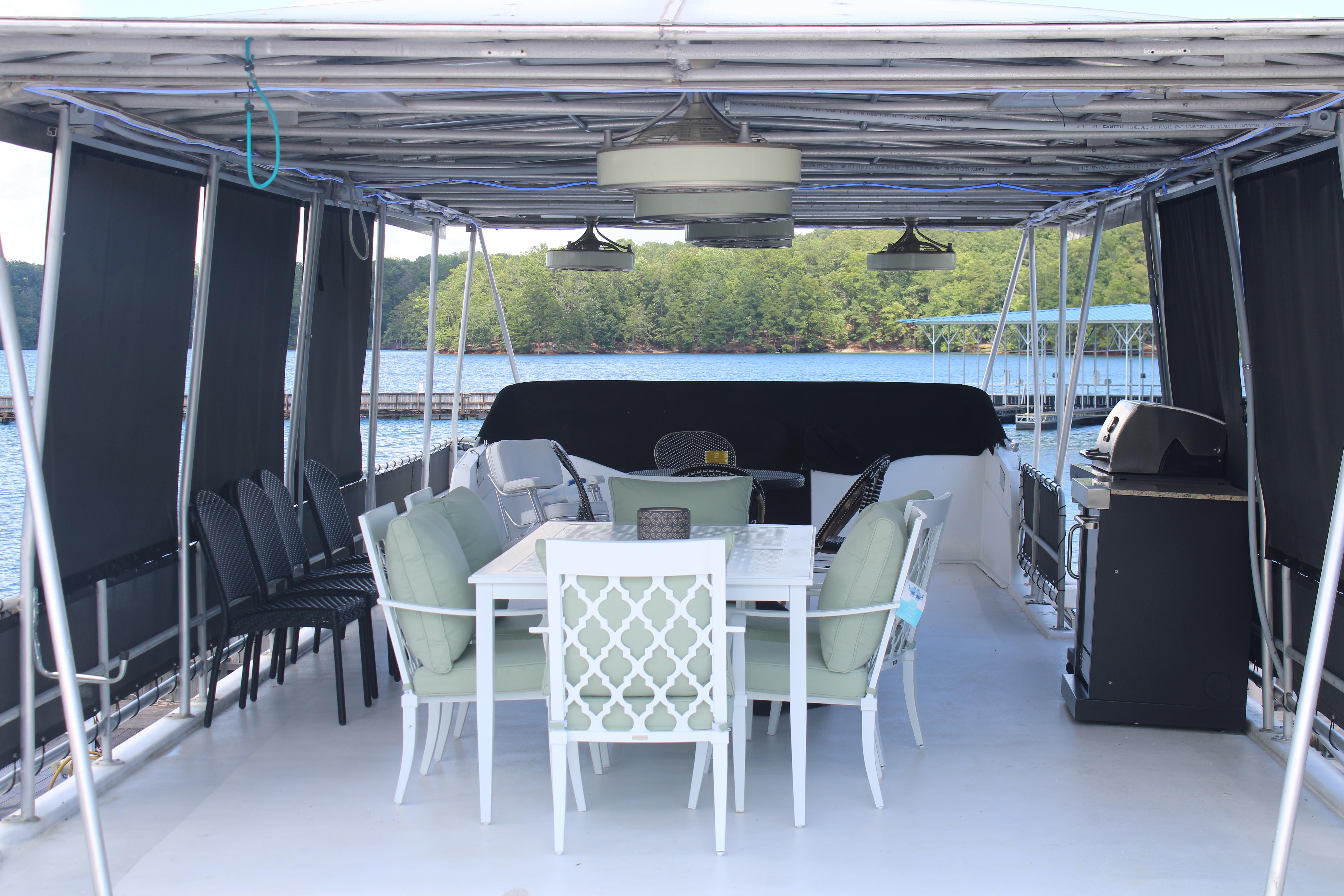 Outdoor seating area on a 1992 Sumerset 66 houseboat with lake view.