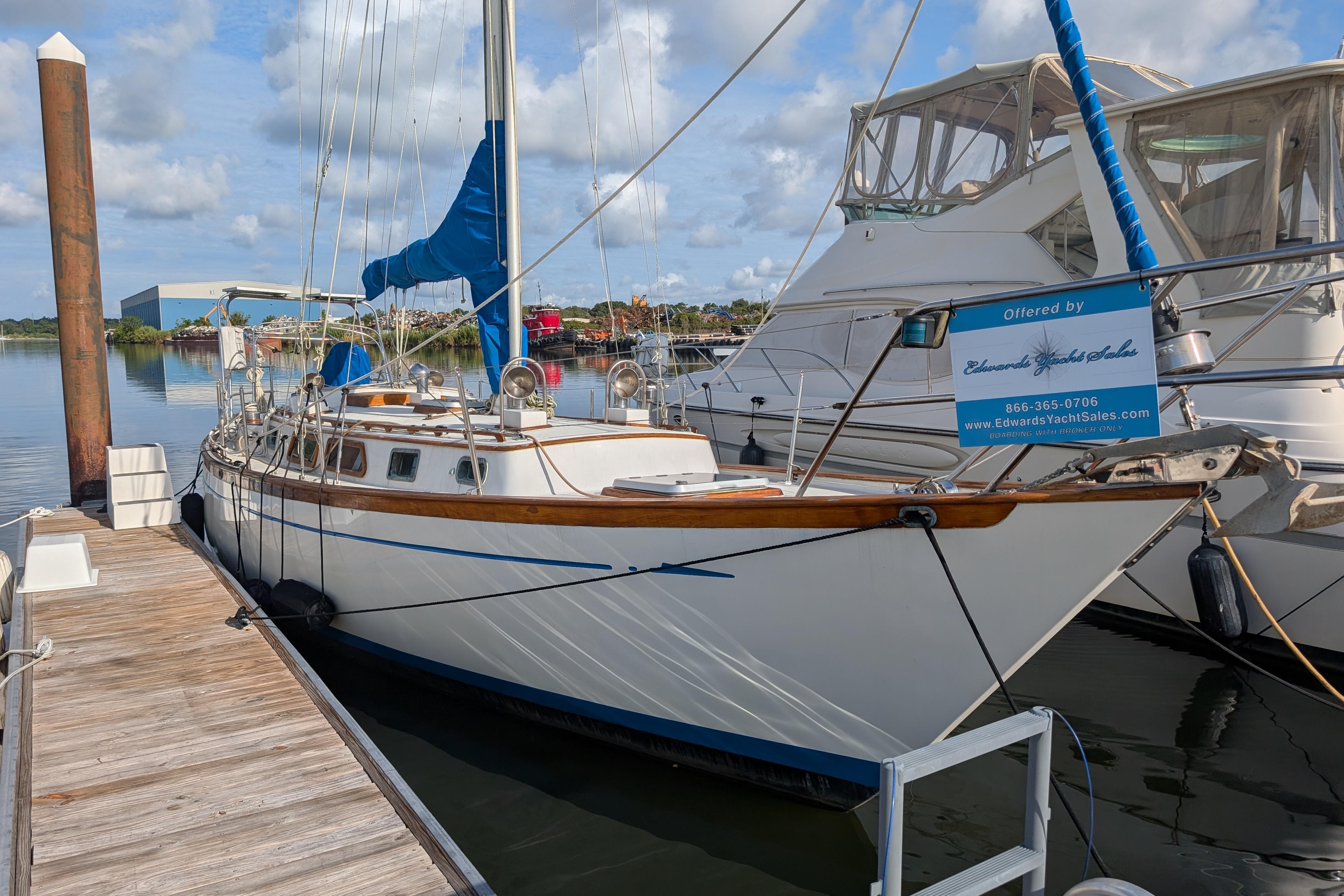 1983 Robert Perry 41 sailboat docked at marina, clear sky, calm water.
