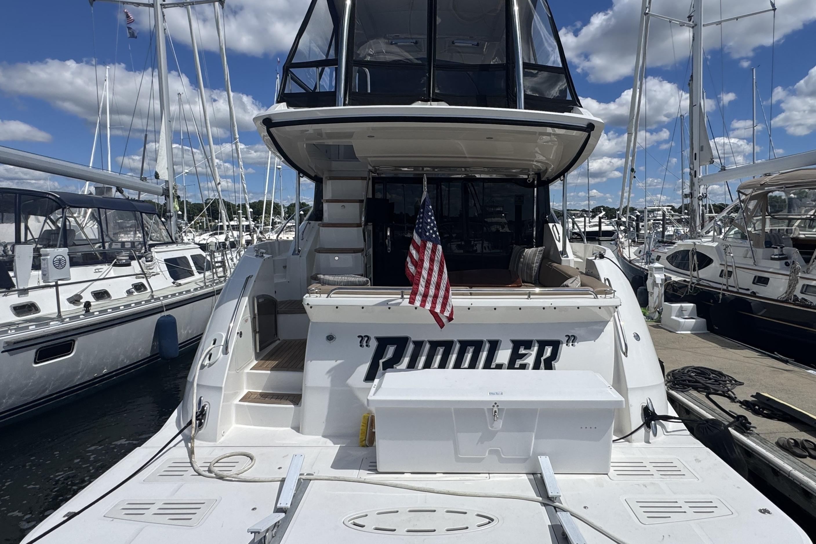 2016 Sea Ray L590 Fly yacht docked, featuring spacious deck and American flag.