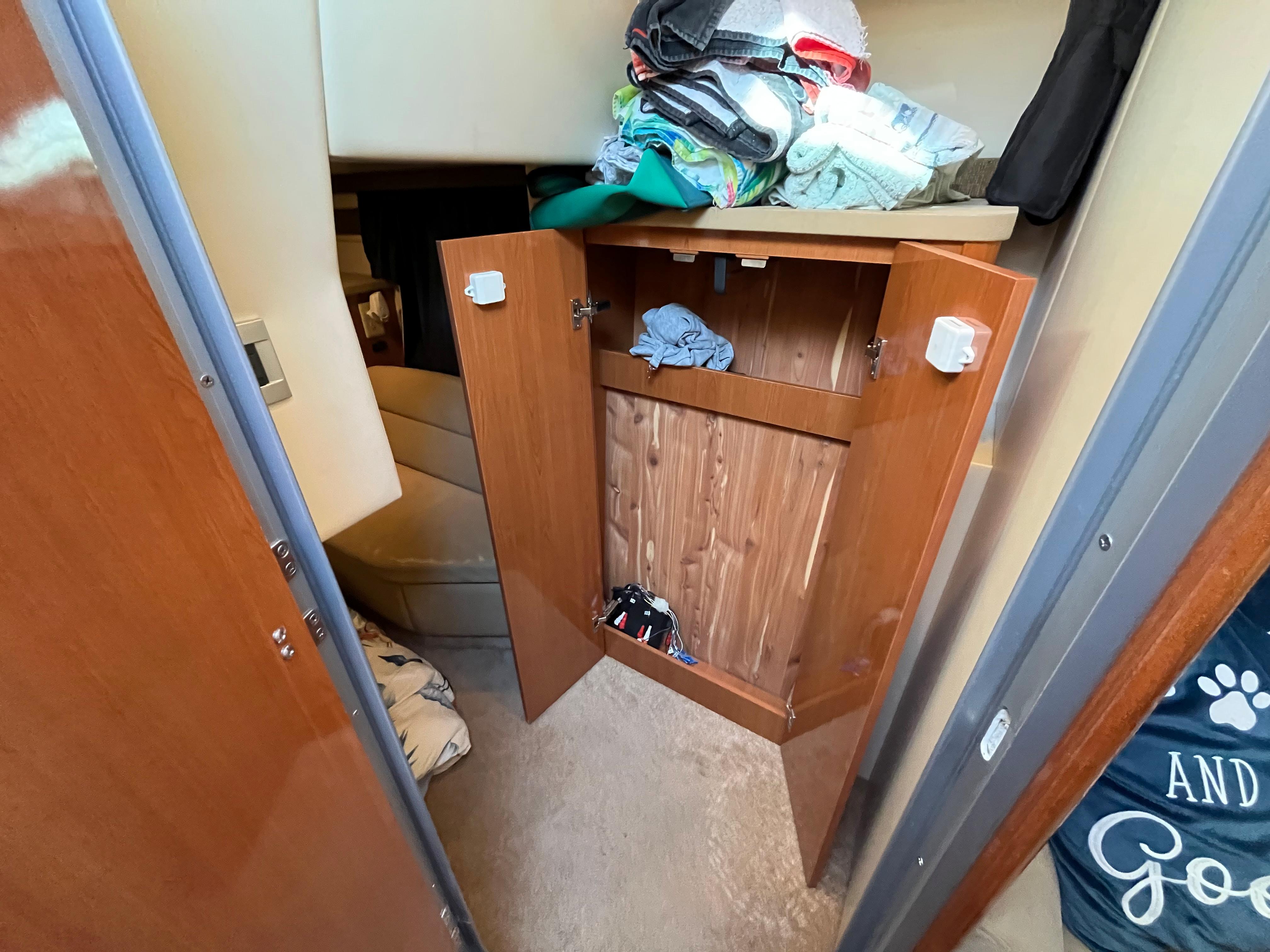 Open cabinet in 2009 Maxum 3100 SE boat interior with clothes.