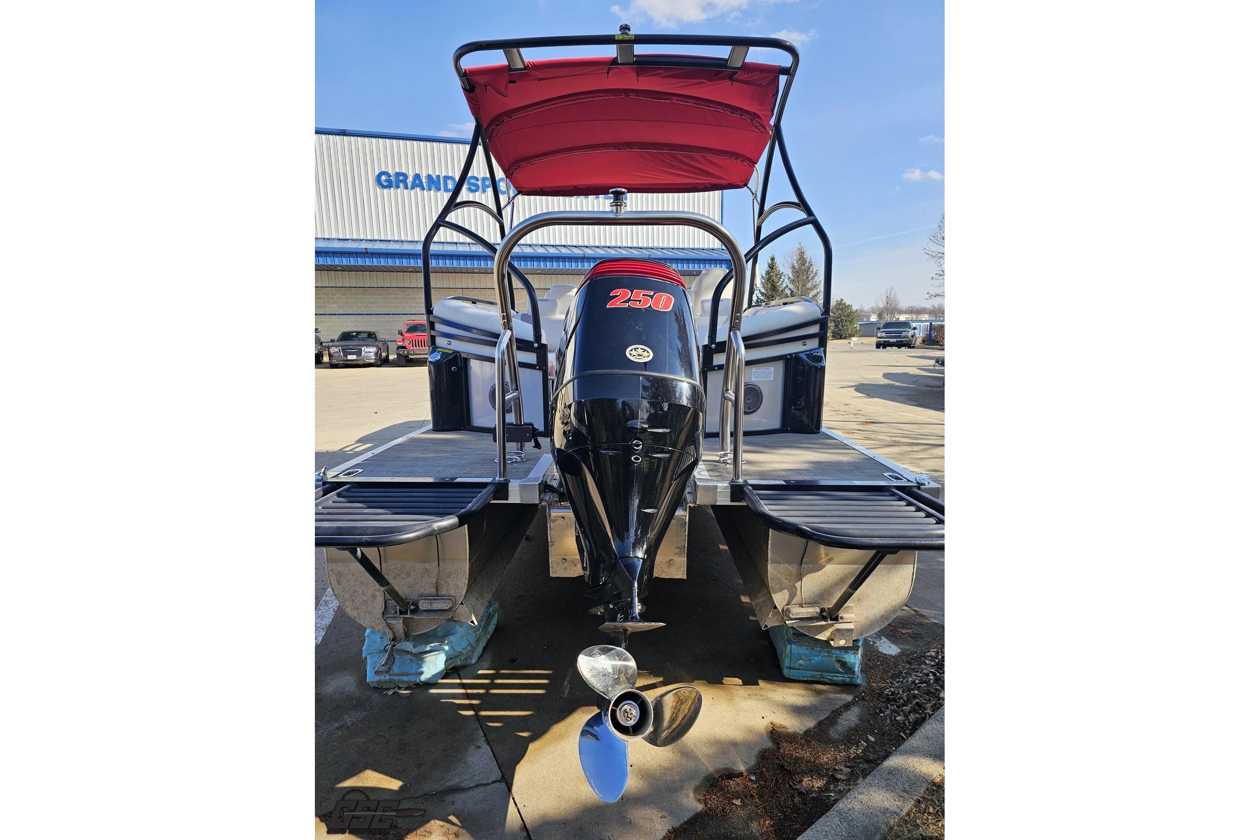 2019 JC Tritoon Neptoon 25 Sport SL with powerful outboard motor, parked outdoors.