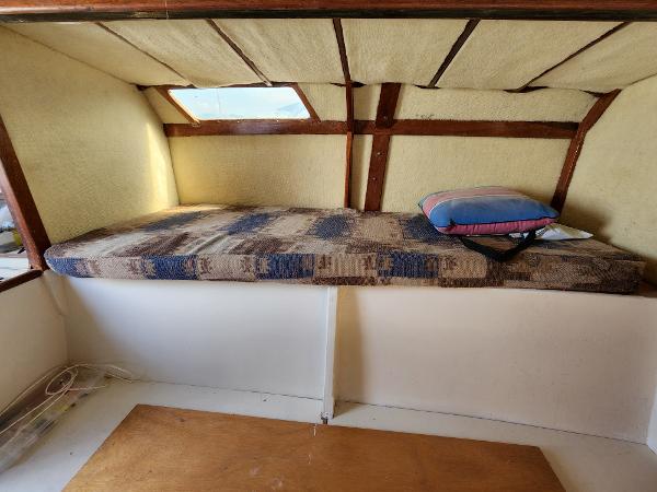 1985 Crowther Buccaneer interior cabin with bed, wooden accents, and a small window.