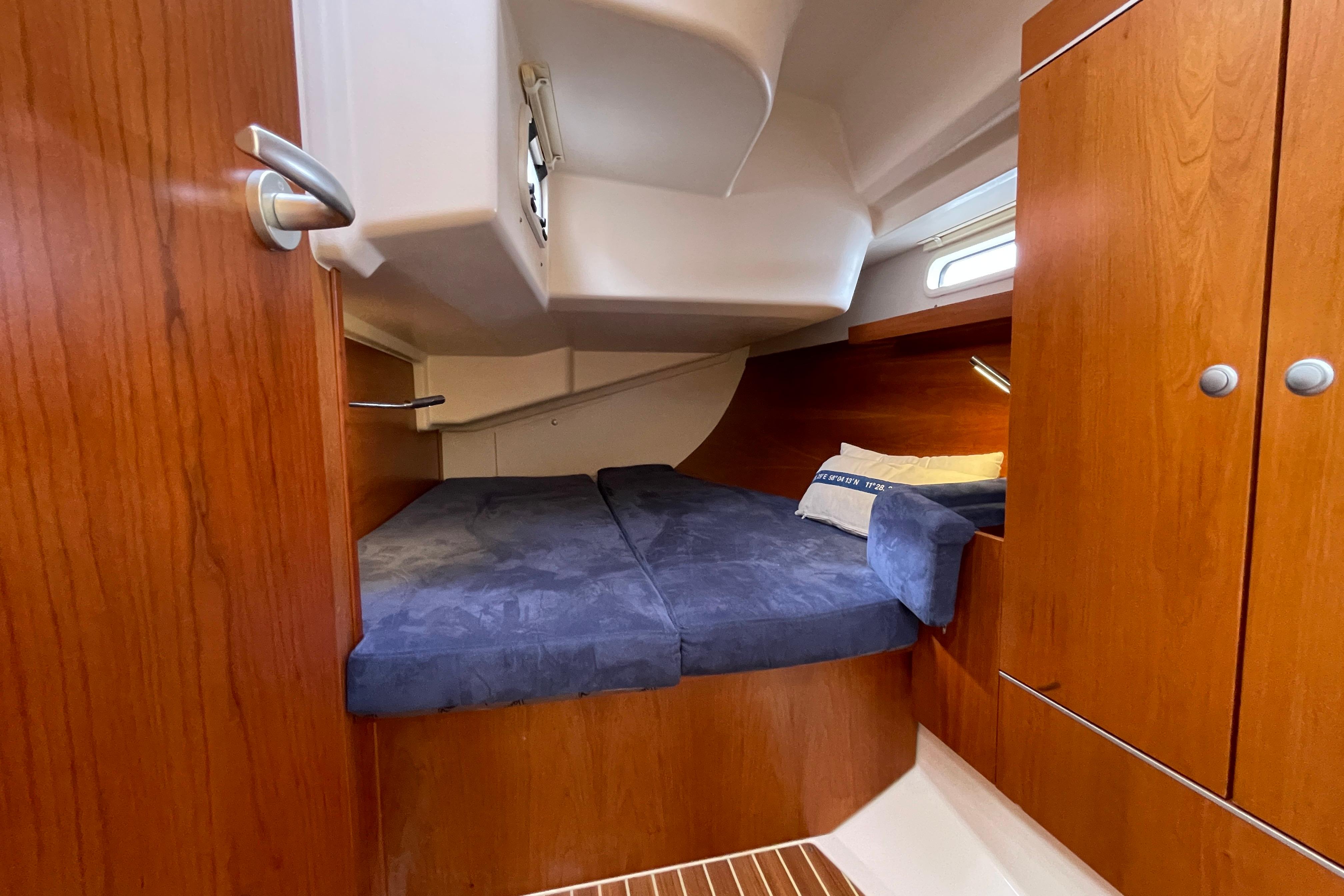 Cozy cabin interior of 2014 Hanse 415 yacht with wooden finish and blue bedding.