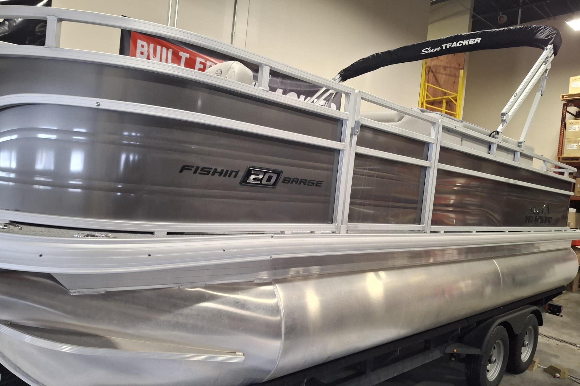 2026 Sun Tracker Party Barge 20 DLX pontoon boat on trailer in showroom.