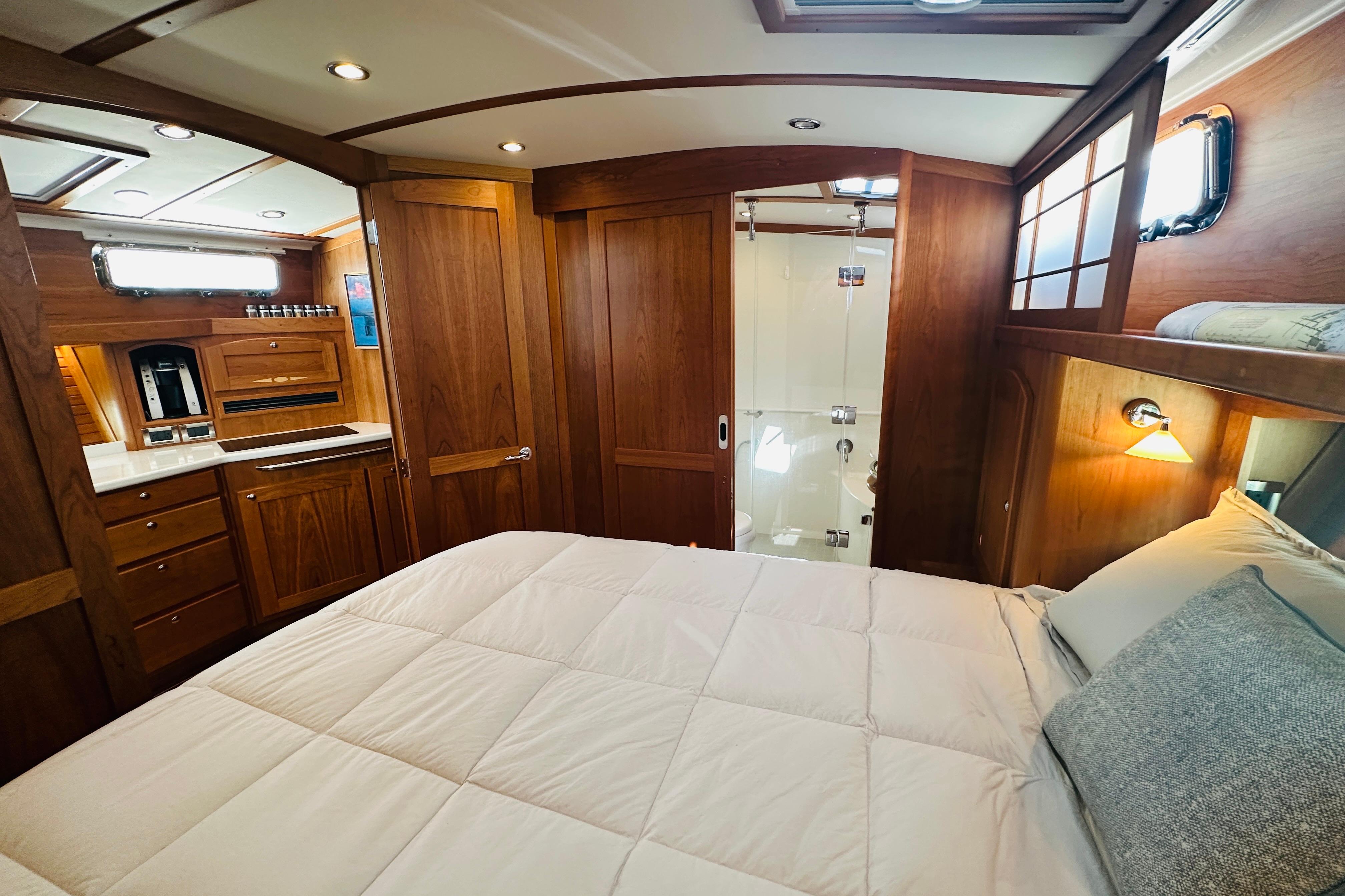 Luxurious interior of 2025 Sabre 48 Salon Express yacht with wood finish and cozy bedding.