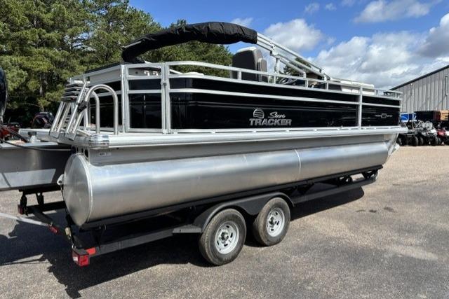 2026 Sun Tracker Fishin' Barge 22 DLX pontoon boat on trailer, parked outdoors.