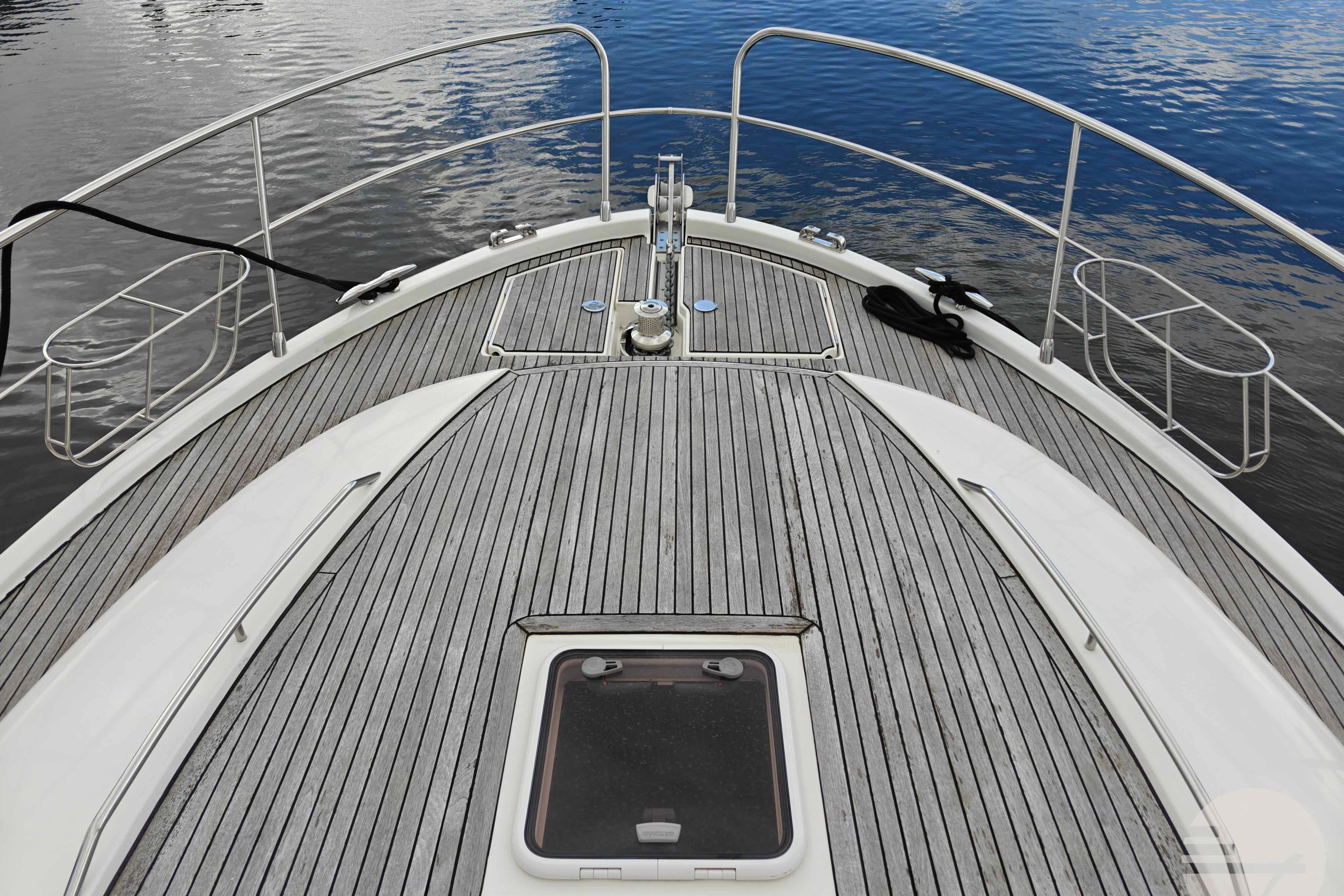 Bow view of 2006 Jeanneau Prestige 46 yacht with teak decking on calm water.