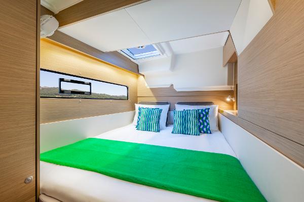 Modern cabin interior of 2025 Lagoon 38 catamaran with green bedding and striped pillows.