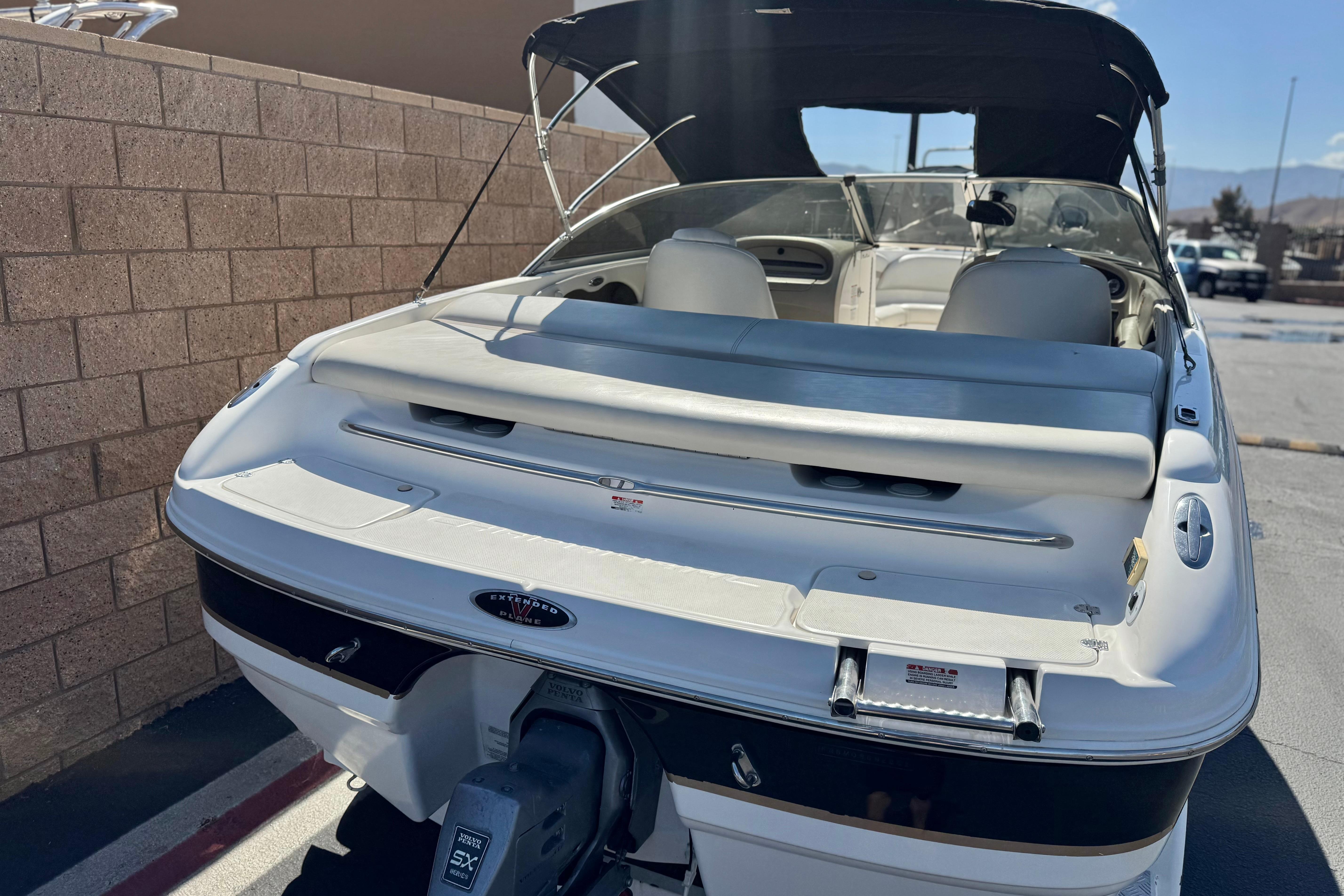 2002 Chaparral 186 SSi boat with extended swim platform, parked near a brick wall.