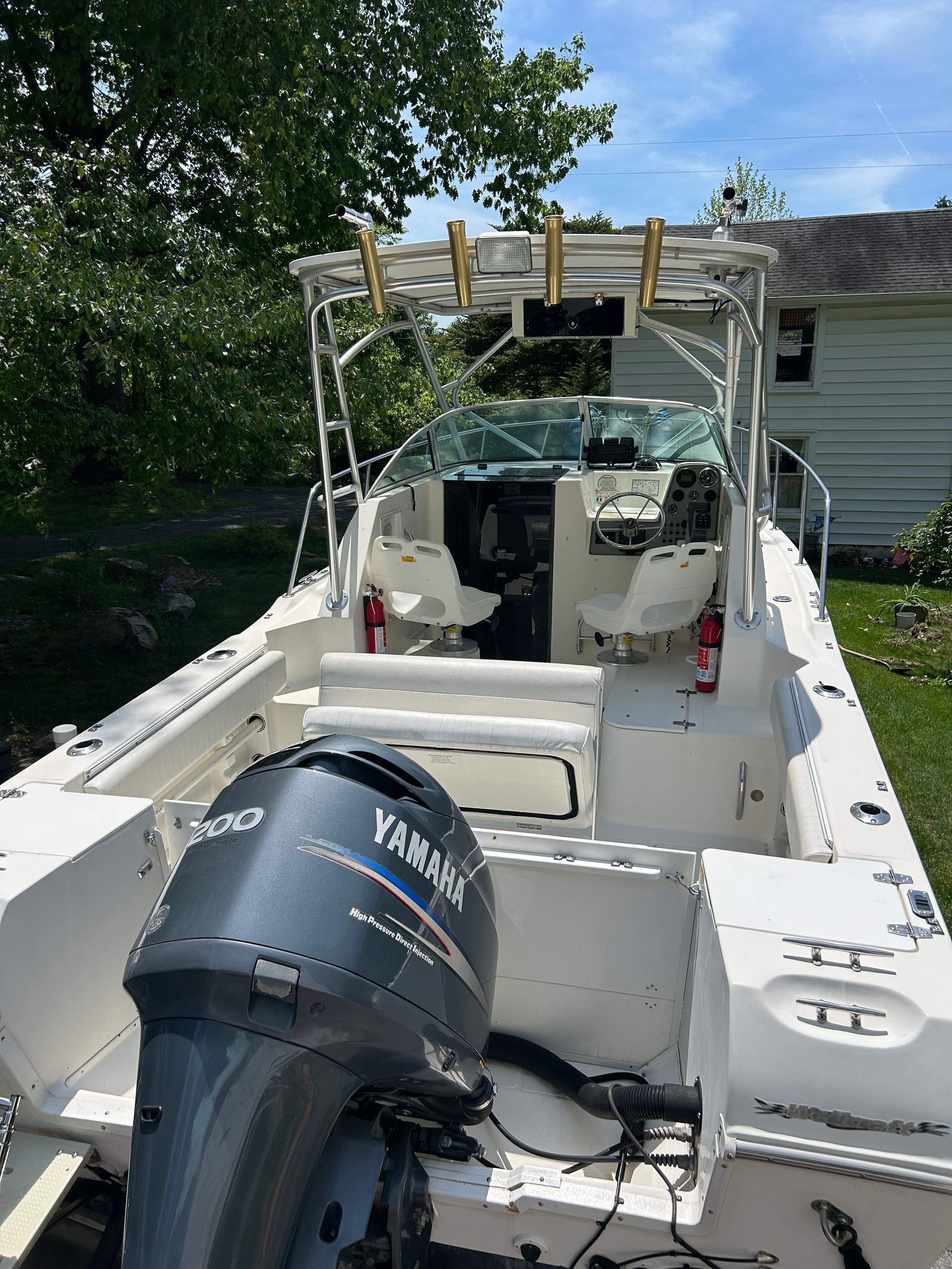 A 2002 Wellcraft 24 Walkaround boat with Yamaha outboard motor, two seats, and fishing rod holders.
