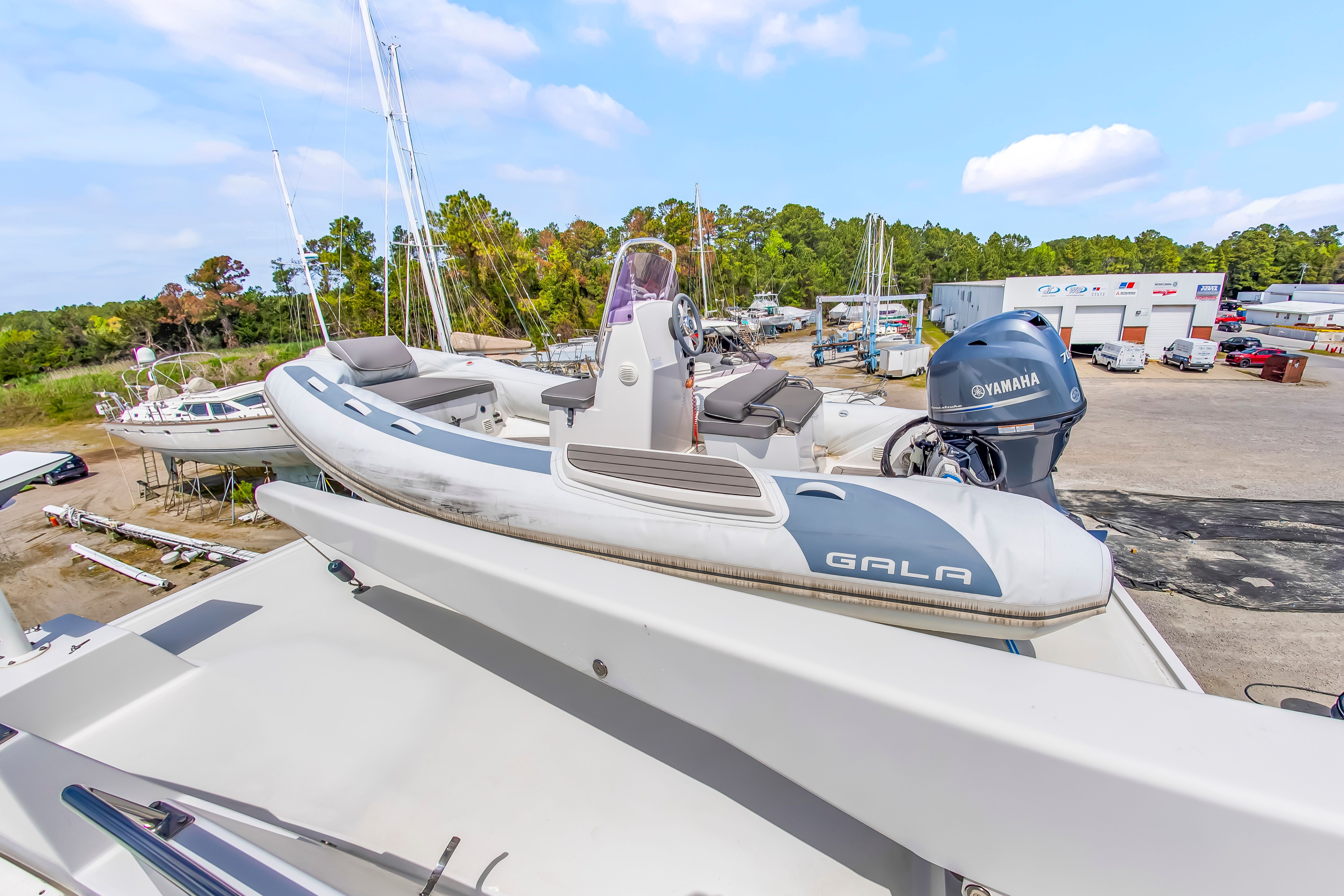 A tender with a Yamaha engine is mounted on a larger boat, surrounded by trees and buildings.