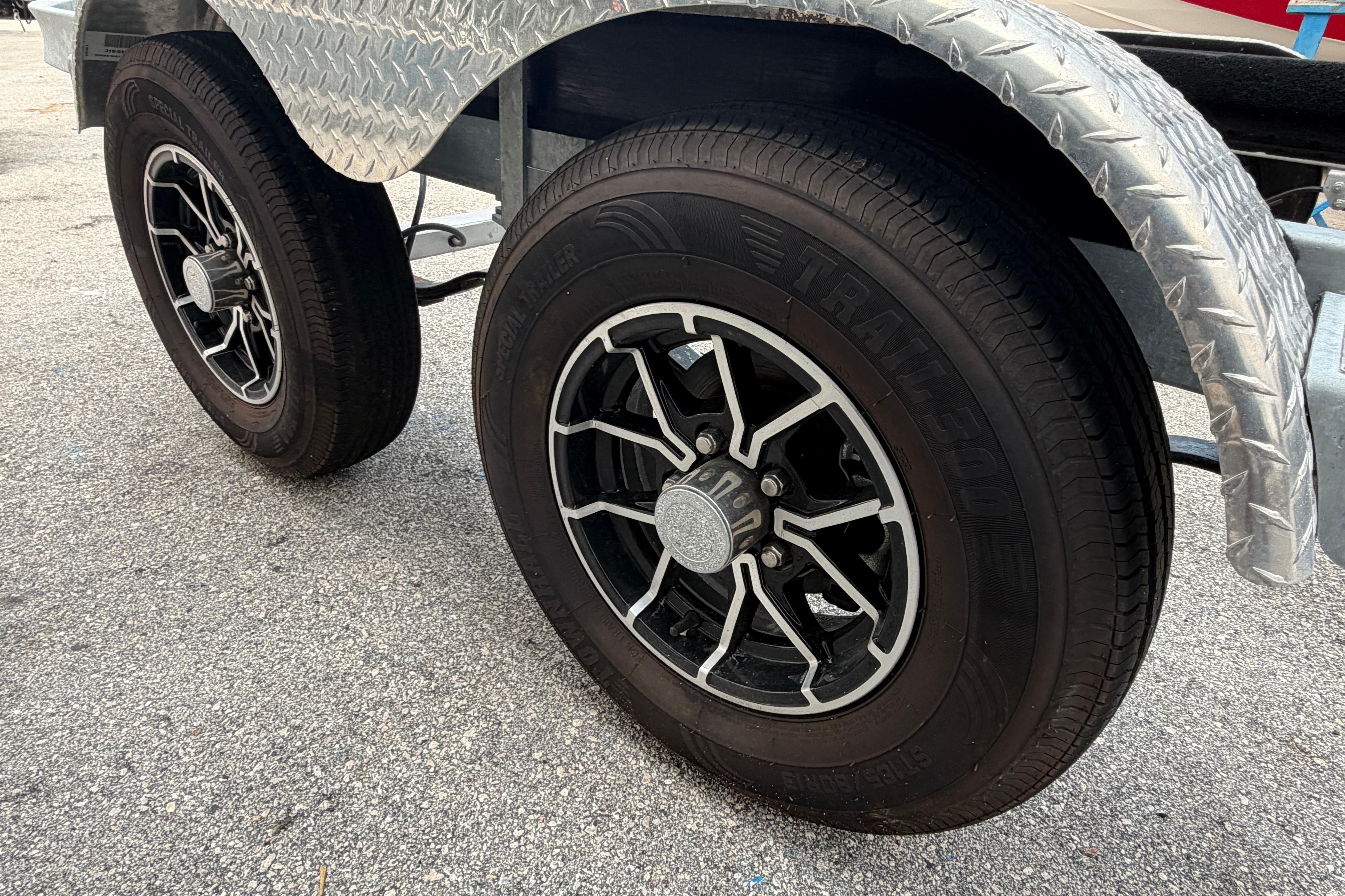 Trailer wheels with black alloy rims on a 2024 SRT5000, parked on asphalt.