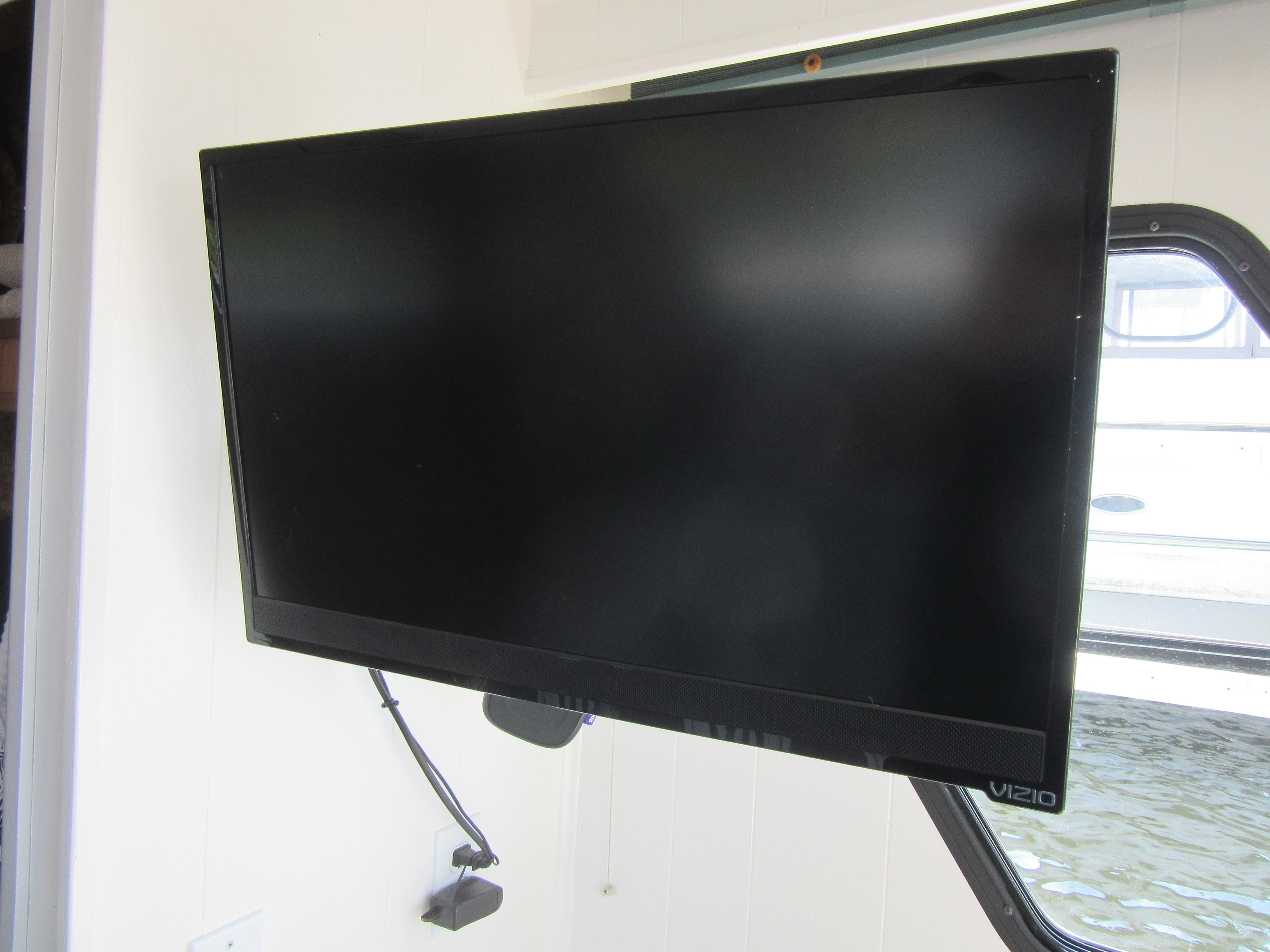 Flat-screen Vizio TV mounted on a wall in a bright room.