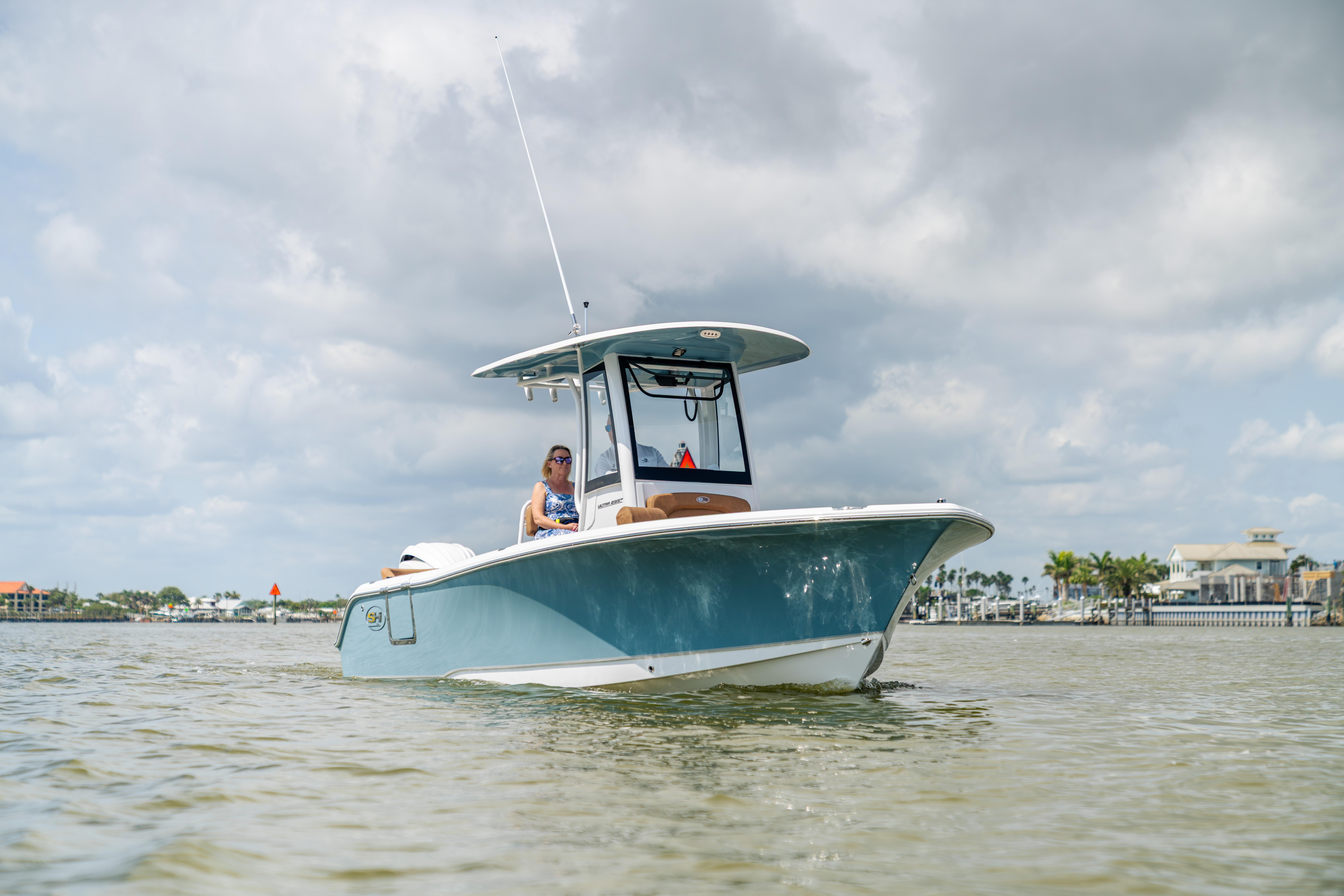 2026 Sea Hunt Ultra 235 SE boat on calm water under cloudy sky.