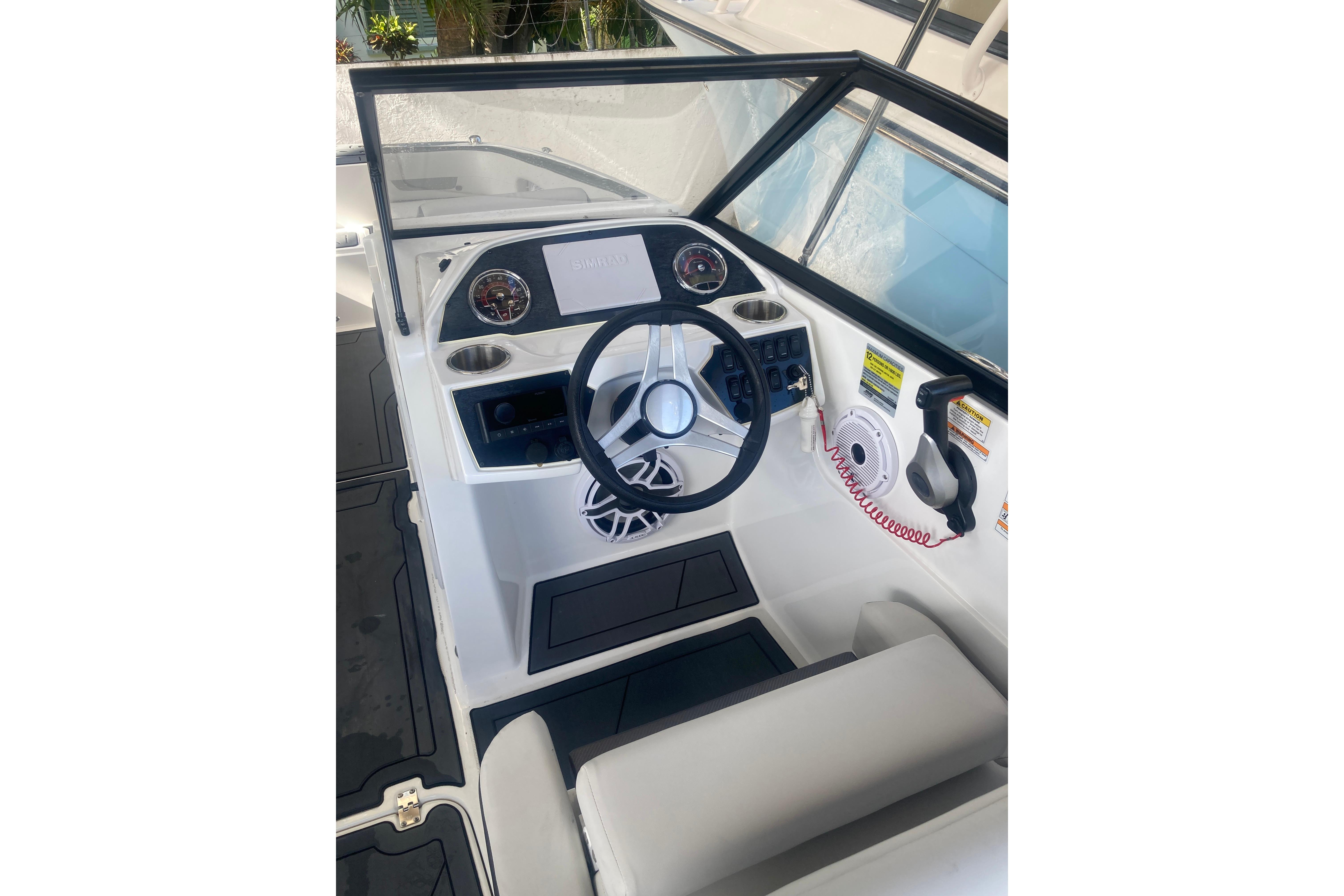 2023 Hurricane SunDeck 235 OB boat cockpit with steering wheel and control panel.