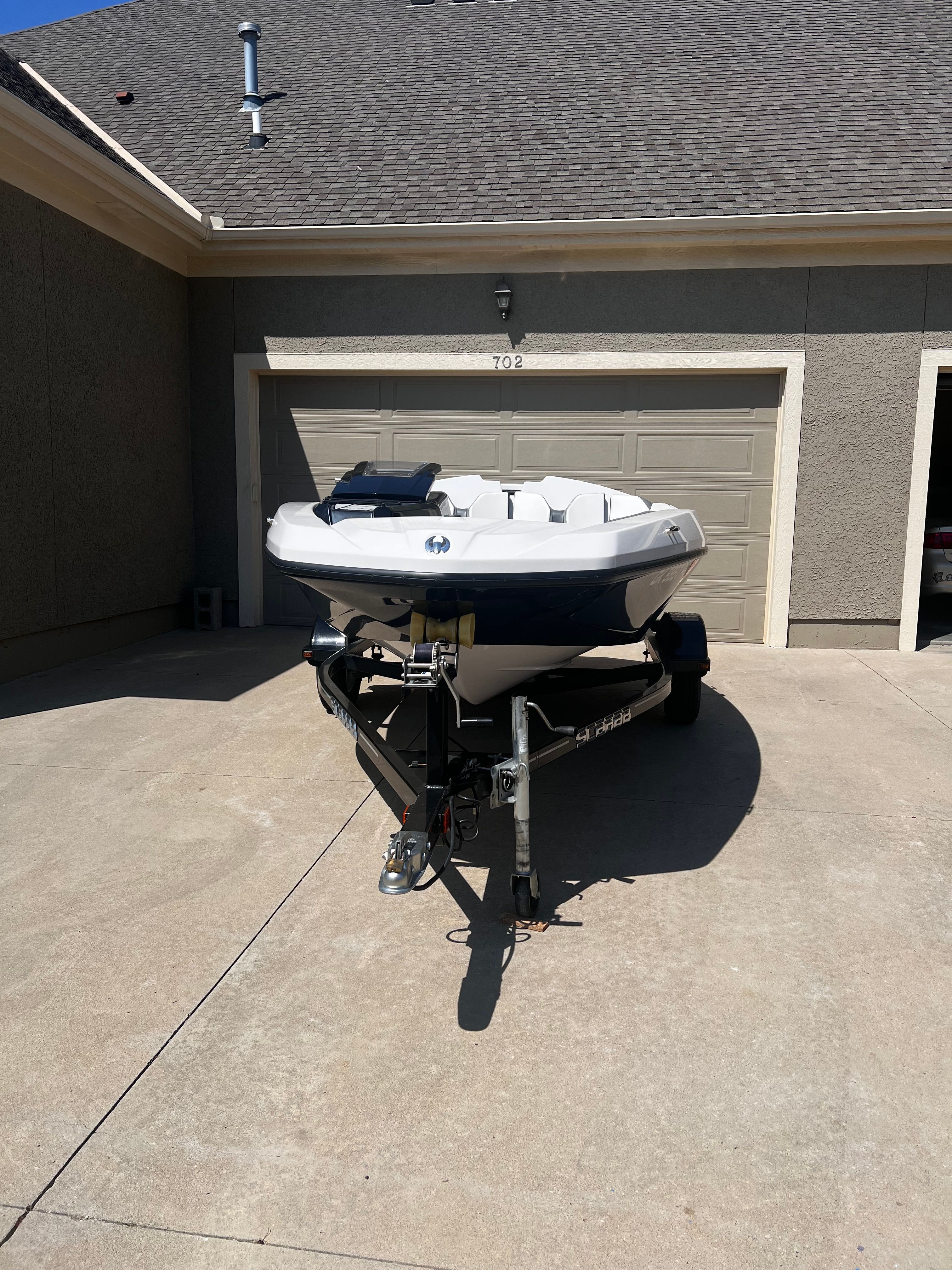 A 2019 Scarab 165 G boat is on a trailer in a driveway.