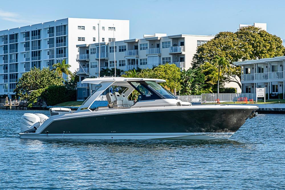 2023 Tiara Yachts 34 LS boat on water near modern buildings.