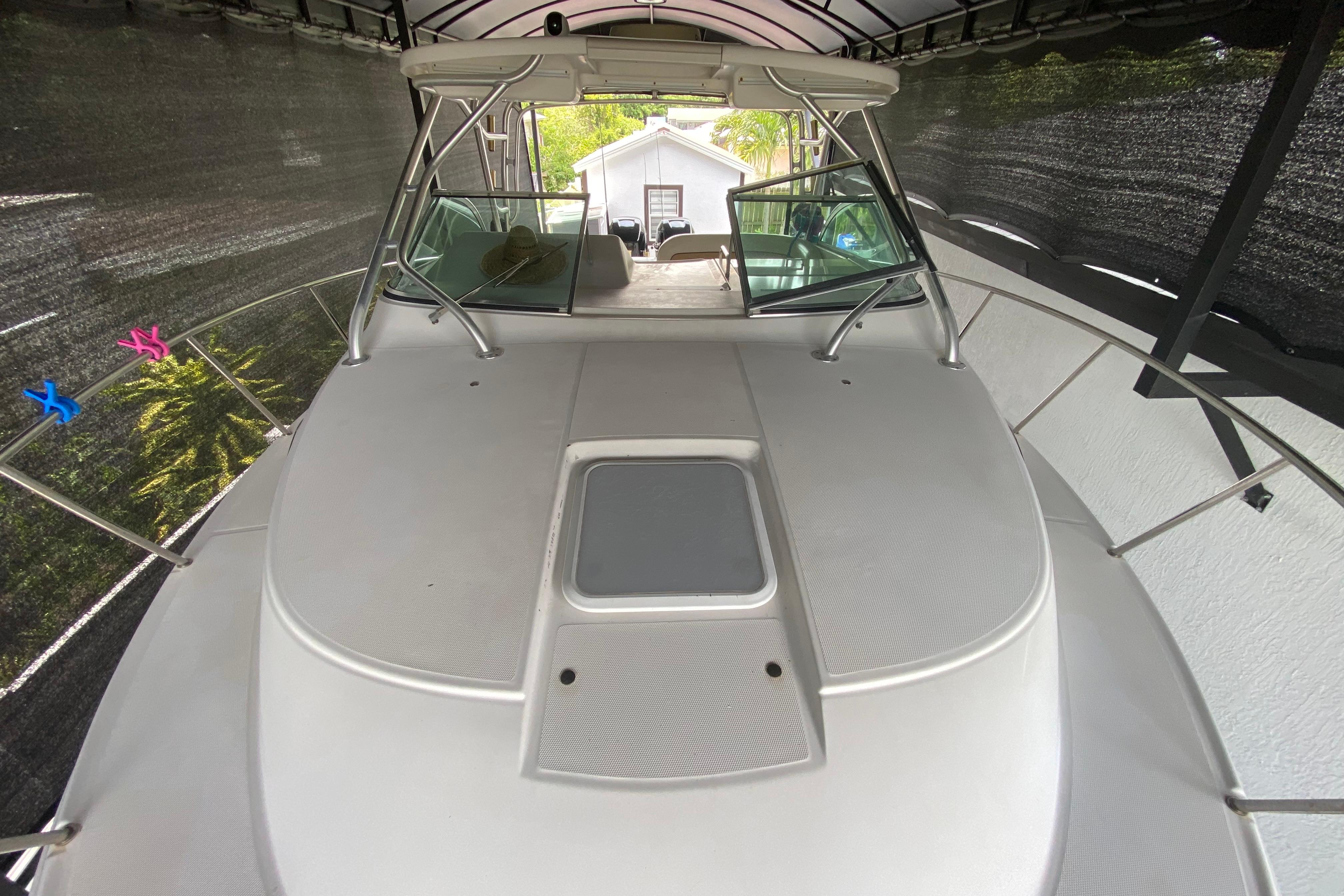 2005 Wellcraft 290 Coastal boat under cover, showcasing spacious deck and windshield.